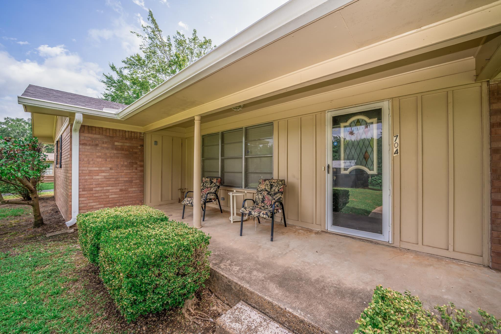 Image 3: Front entrance featuring a covered concrete porch, brick siding, and vertical paneling, Front Porch