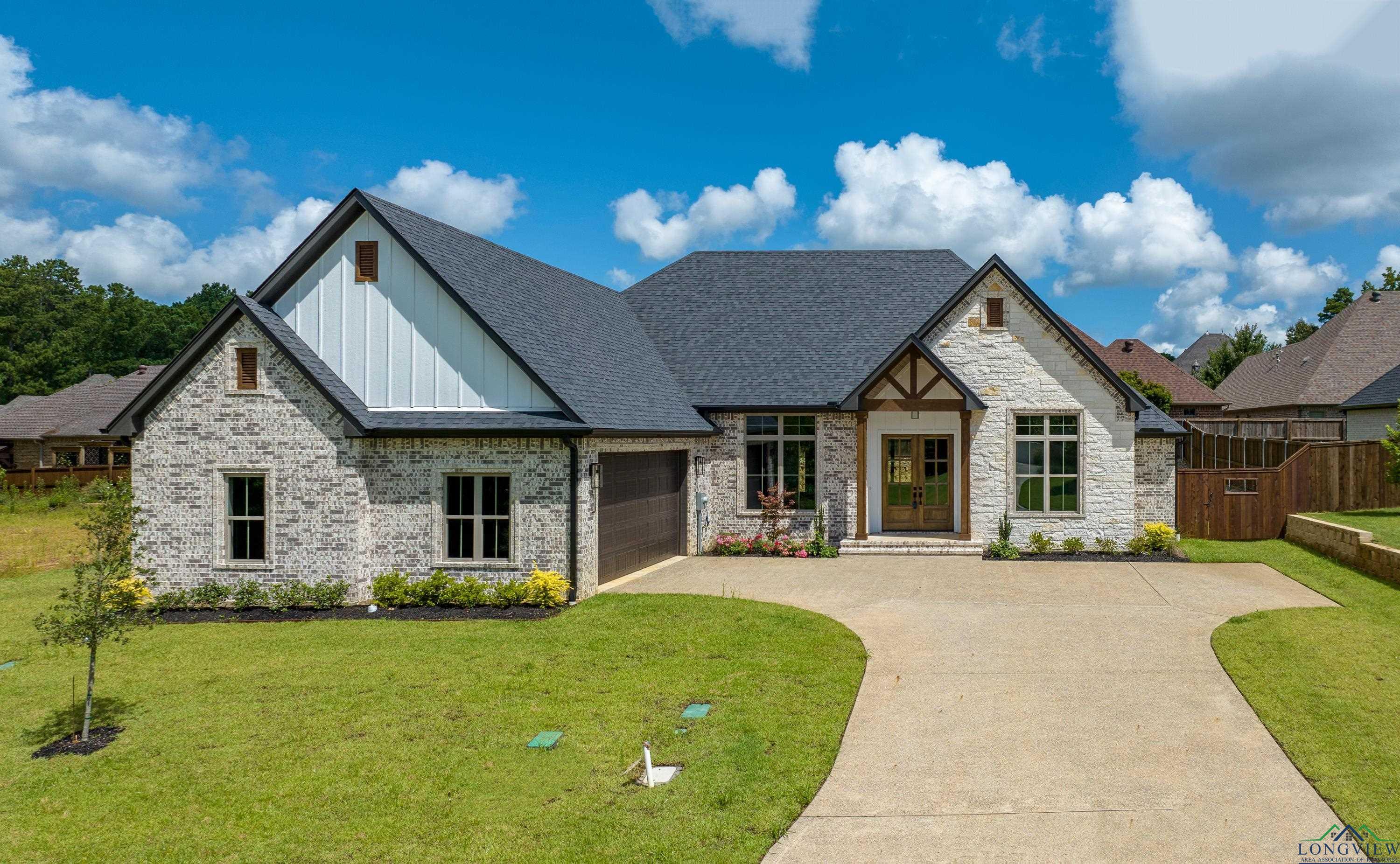 Image 0: View of front of property with board and batten siding, a garage, driveway, stone siding, and a shingled roof, Front Of Structure