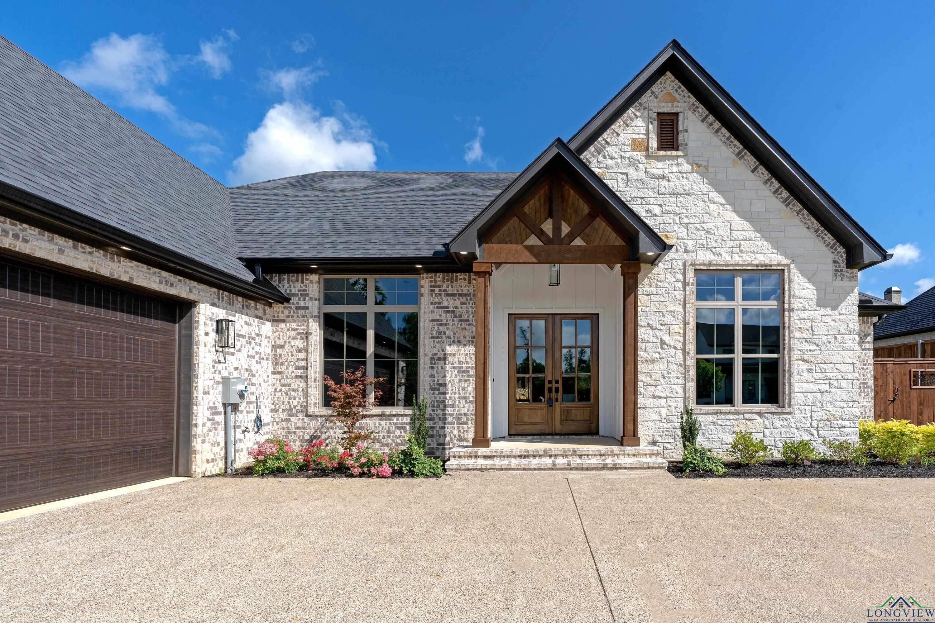 Image 3: Entrance to property featuring french doors, stone siding, a shingled roof, and driveway, Entry