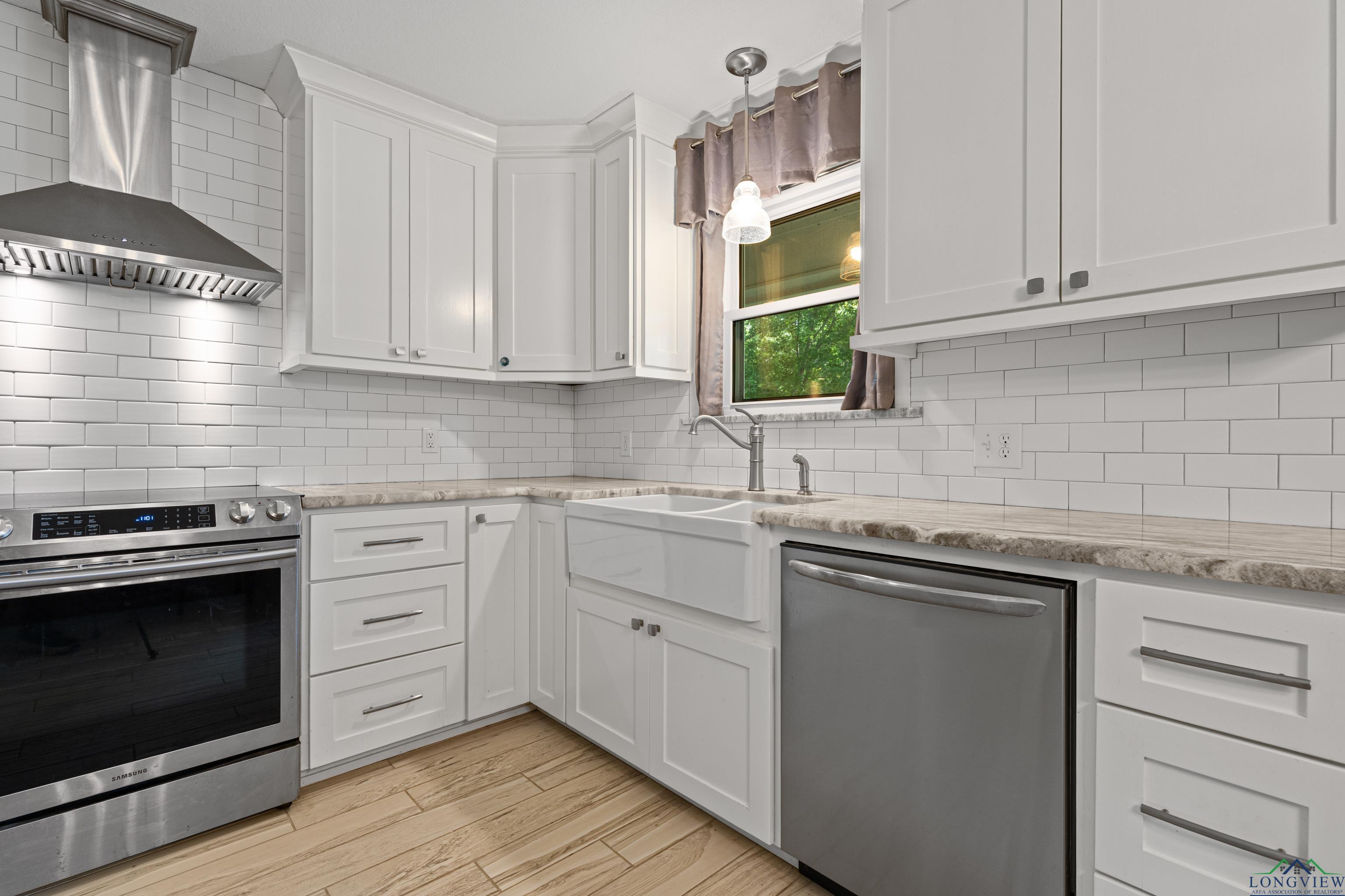 Image 3: Kitchen featuring stainless steel appliances, wall chimney exhaust hood, backsplash, and white cabinets, Kitchen