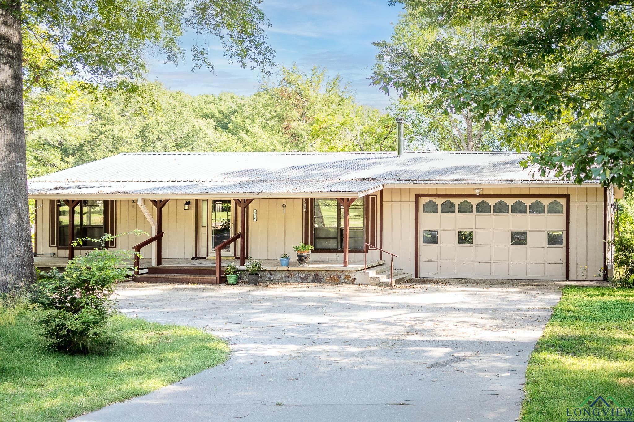 Image 2: View of front of house featuring a porch, driveway, a metal roof, and an attached garage, Front Of Structure