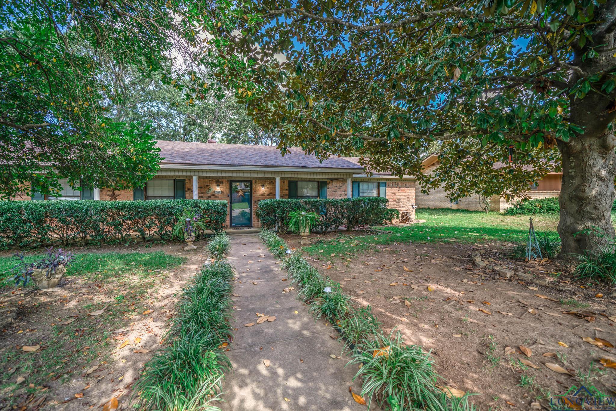 Image 1: Single story home with brick siding, a porch, a shingled roof, and a front yard, Front Of Structure