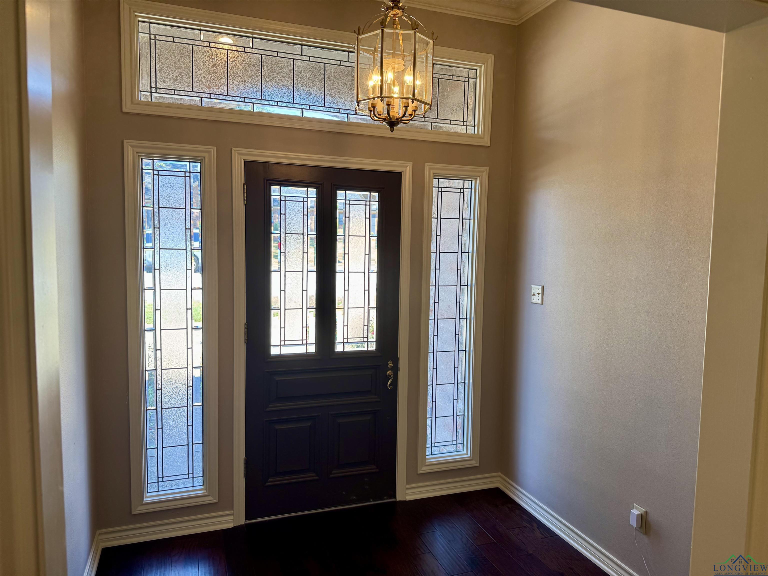Image 3: Entryway with dark wood-style floors, crown molding, and a chandelier, Entrance Foyer