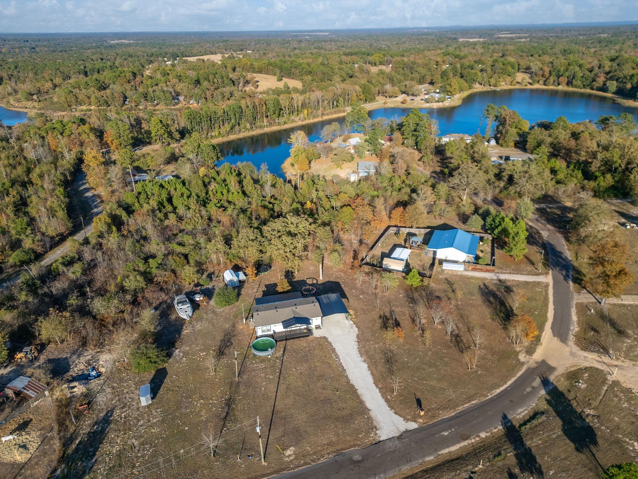 Image 3: Aerial view of property's location featuring a heavily wooded area and a large body of water, Aerial View