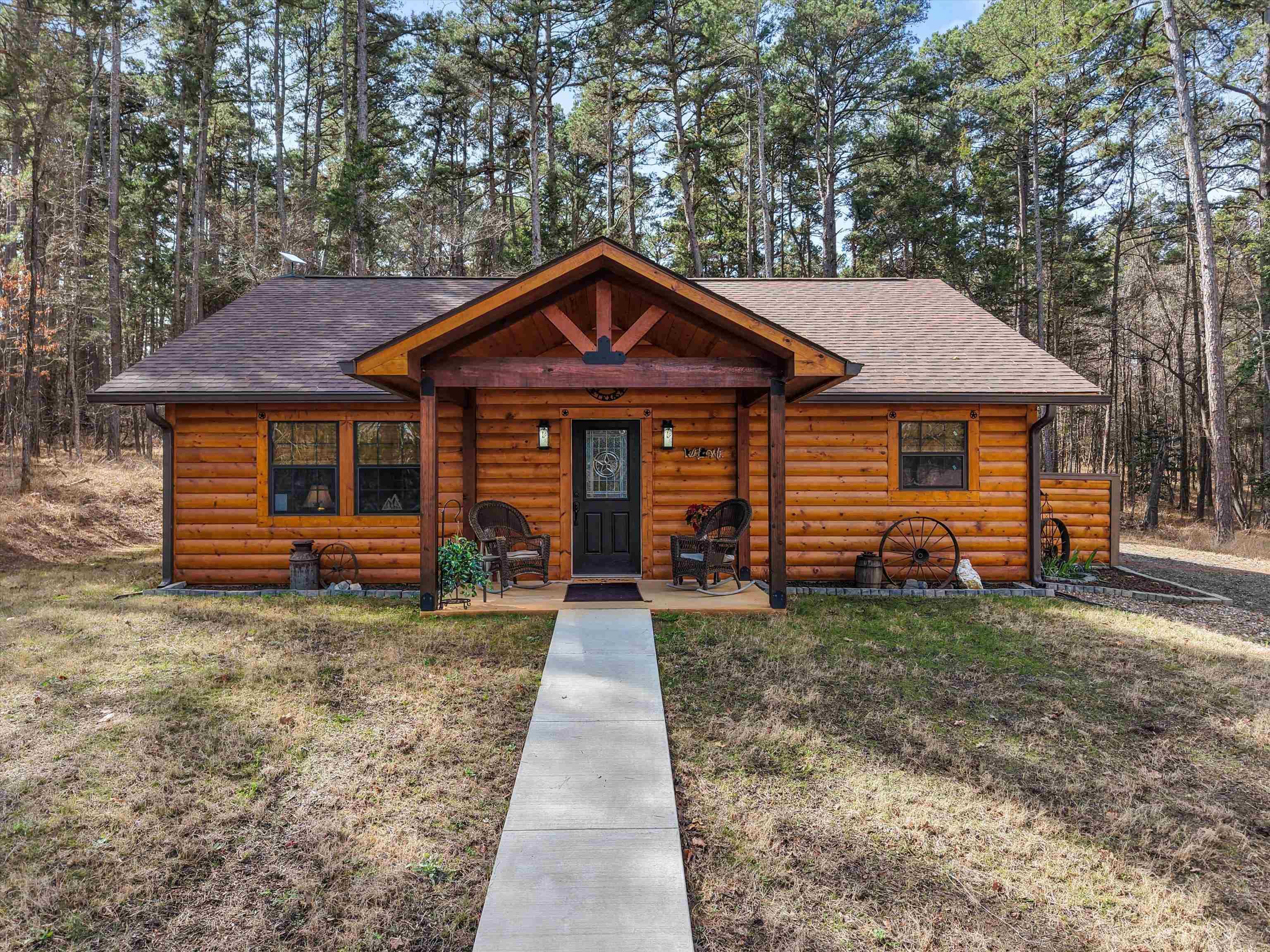 Image 2: View of front of house with faux log siding, a porch, and roof with shingles, Front Of Structure