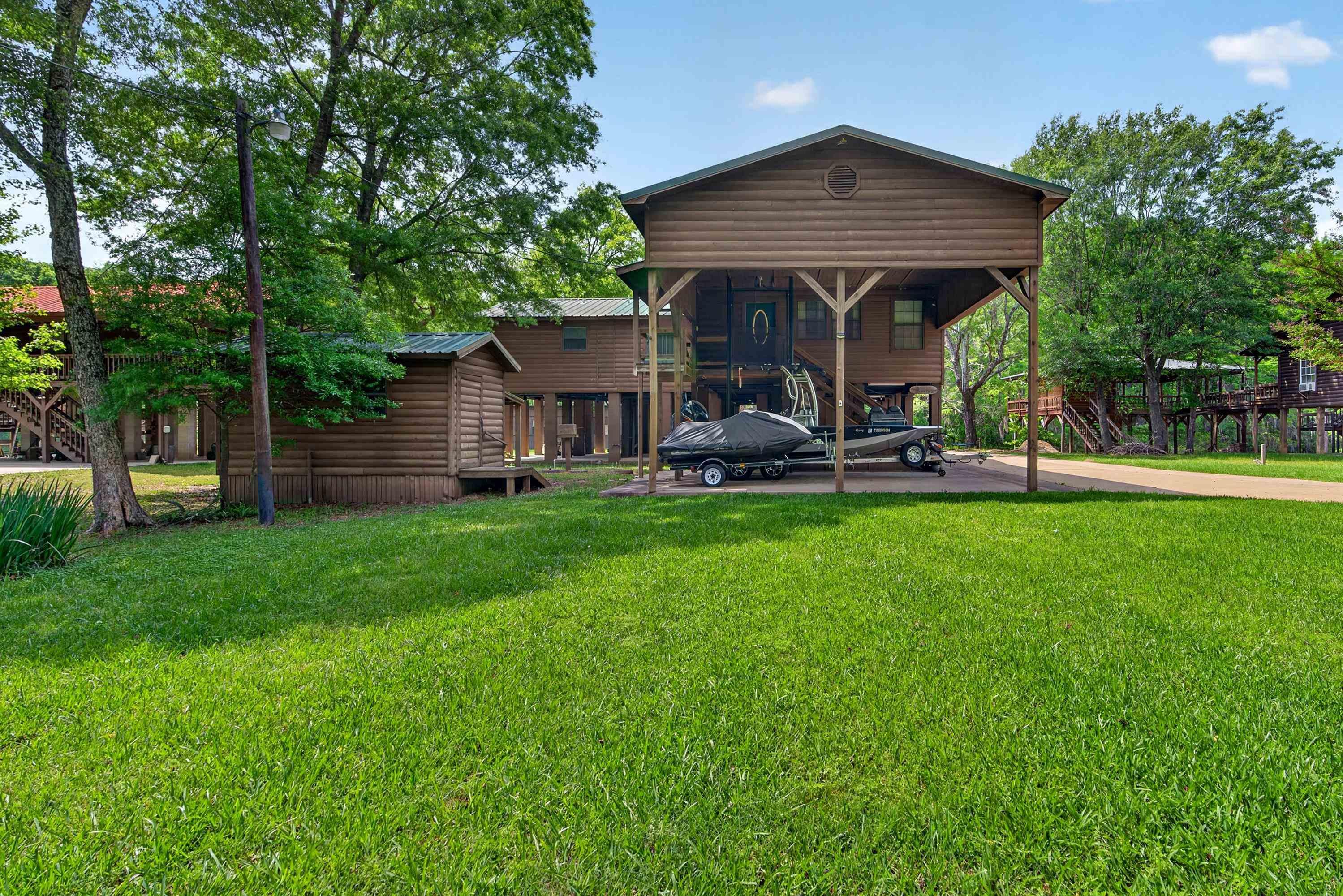 Image 1: Raised wood-sided home featuring a covered parking area with wood support beams