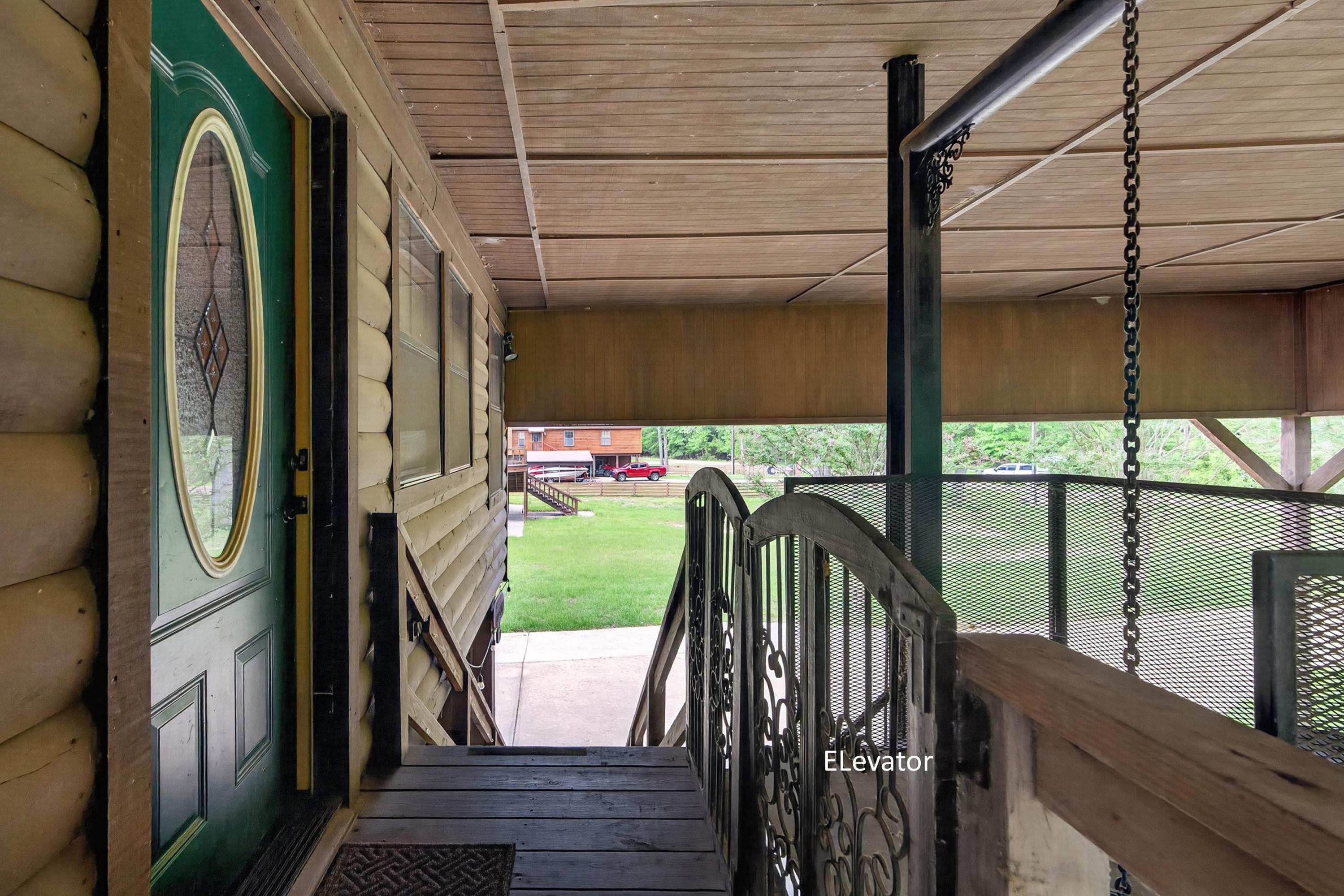 Image 2: Covered outdoor entry area featuring log-style siding and a green entry door with oval glass