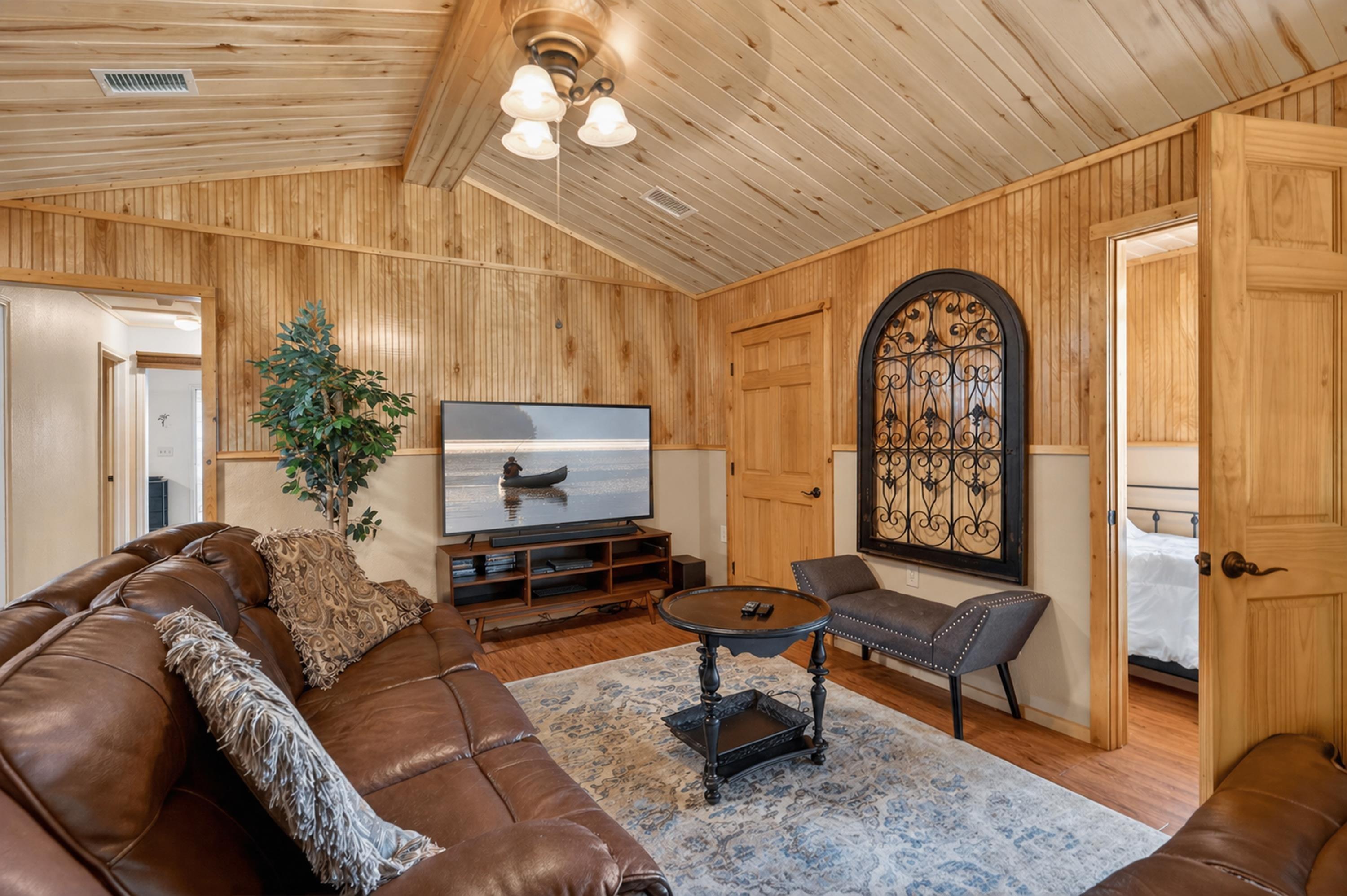 Image 3: Vaulted wood-finish ceilings and paneled walls create a warm interior, Living Room