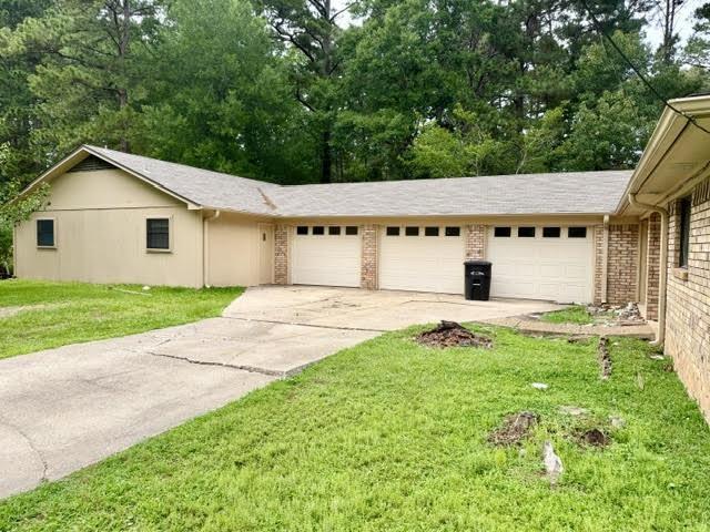 Image 2: Exterior featuring a three-car garage with individual doors, a brick facade, and a pitched roof, Front Of Structure