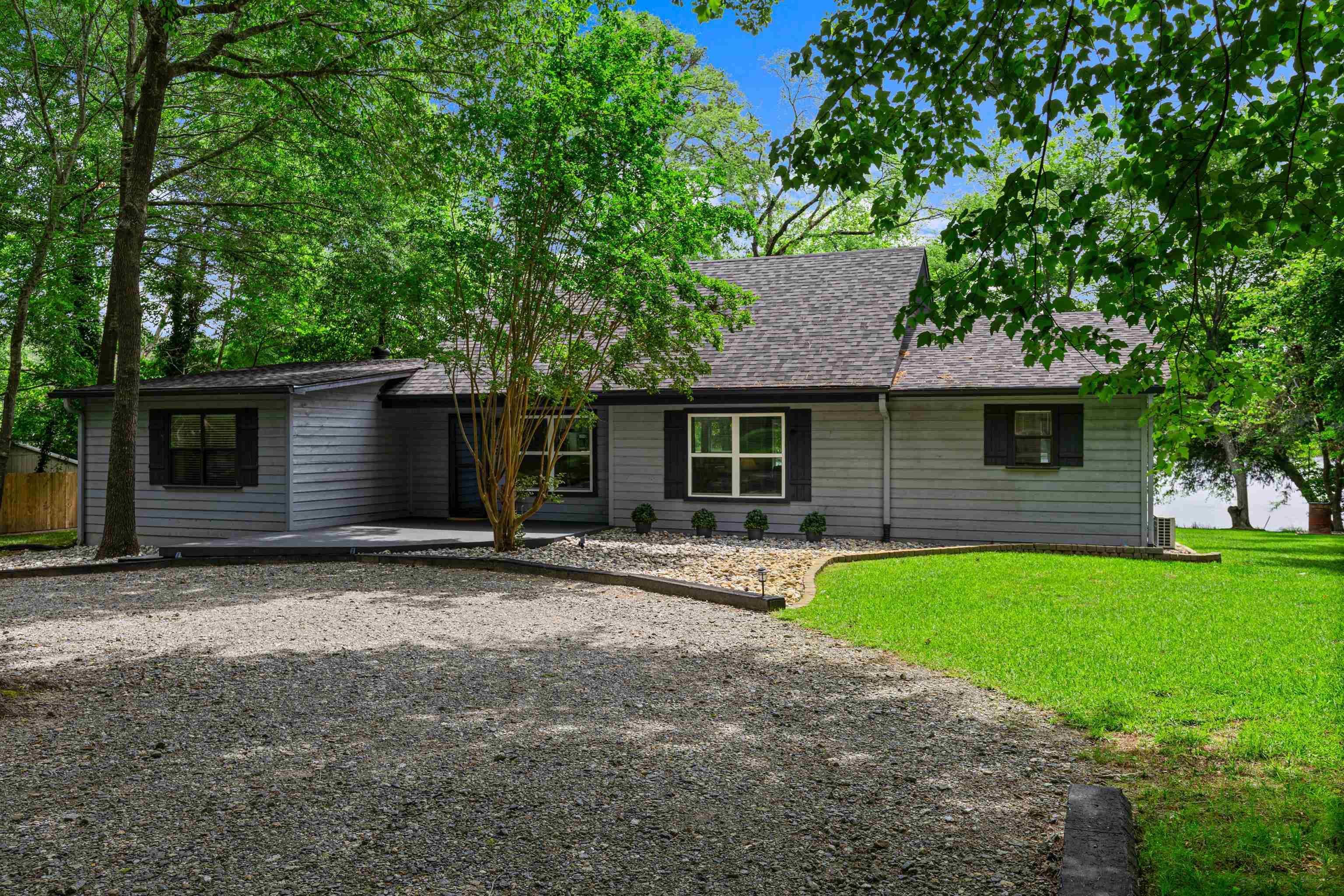 Image 3: Ranch-style residence featuring light gray siding, a dark shingle roof, and black window shutters, Front Of Structure
