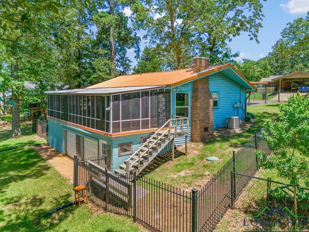 Image 2: Rear view of house featuring a sunroom, a chimney, and a fenced backyard, Back Of Structure