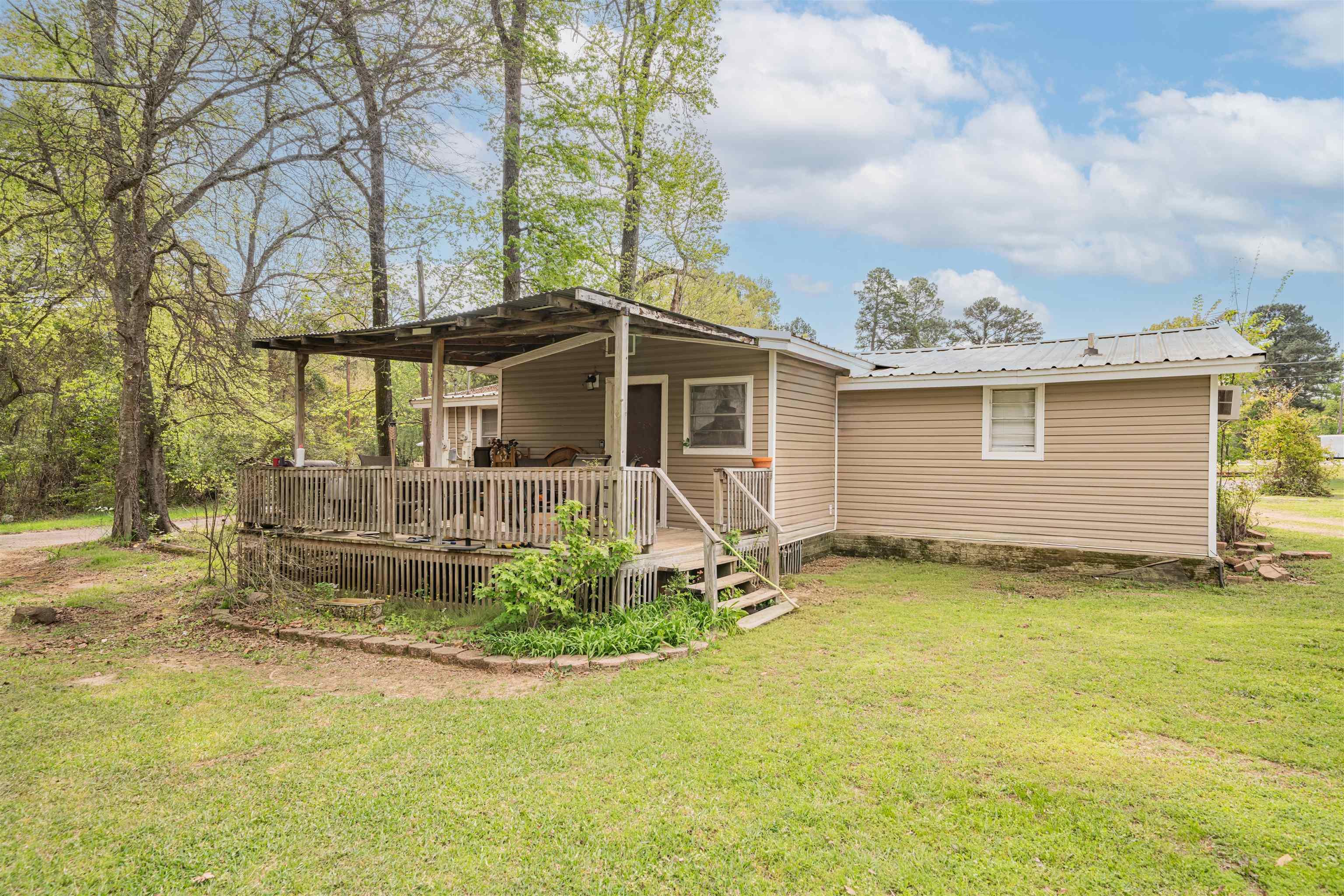 Image 3: Rear view of property featuring a lawn, a wooden deck, and a metal roof, Back Of Structure