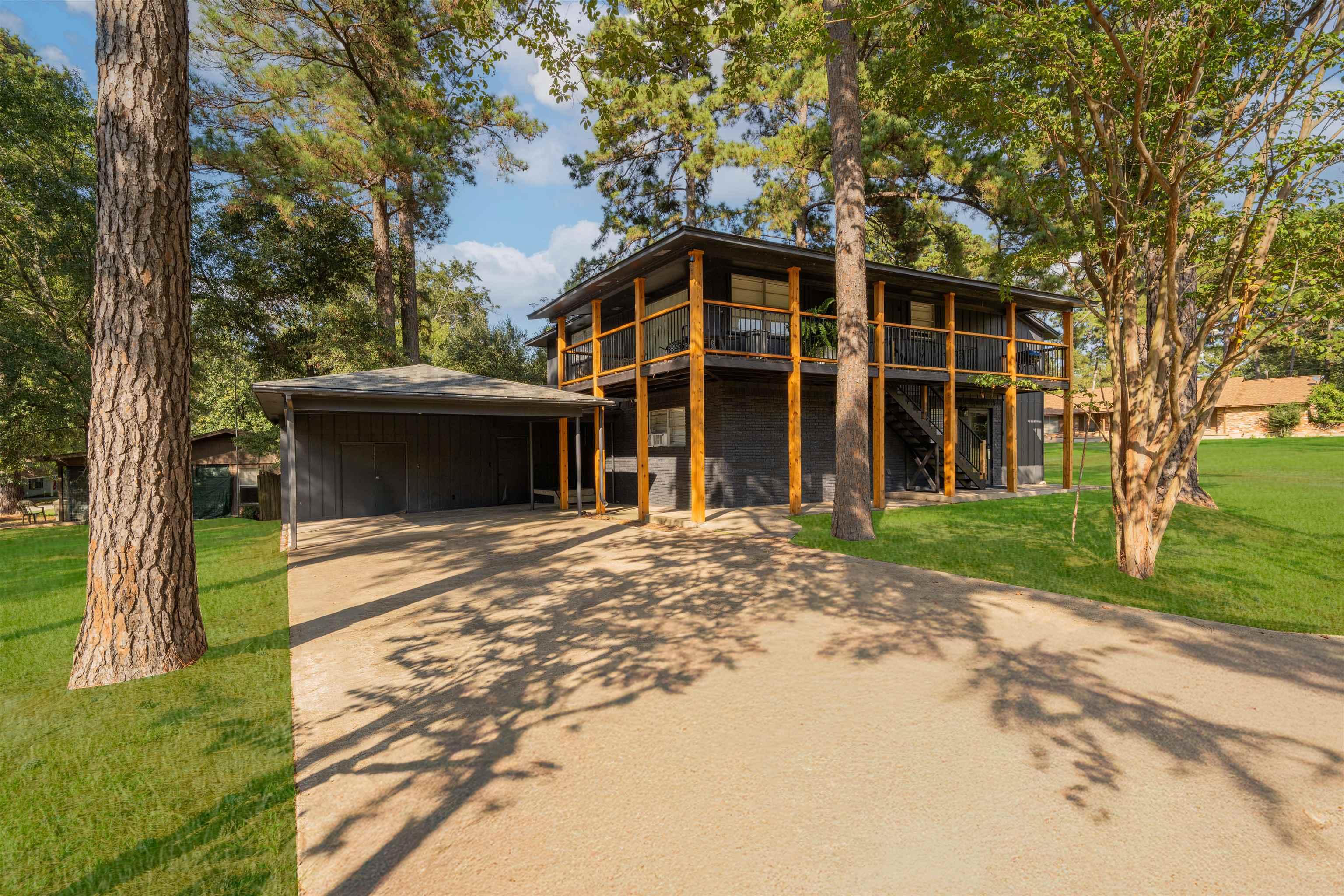 Image 0: View of front of property featuring a front yard, a carport, concrete driveway, stairs, and a deck, Front Of Structure