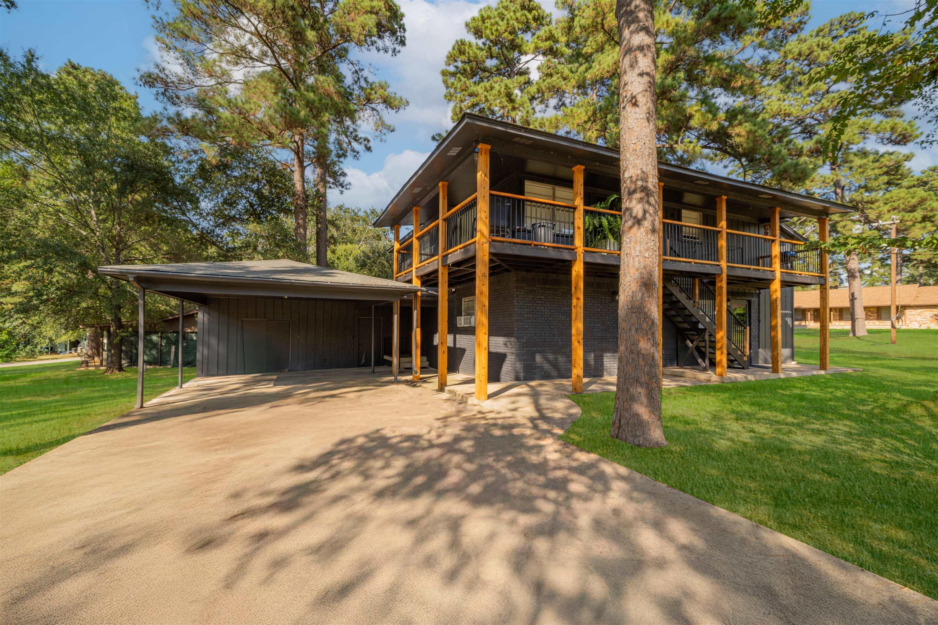 Image 1: View of front facade featuring a front lawn, a carport, driveway, and stairs, Front Of Structure