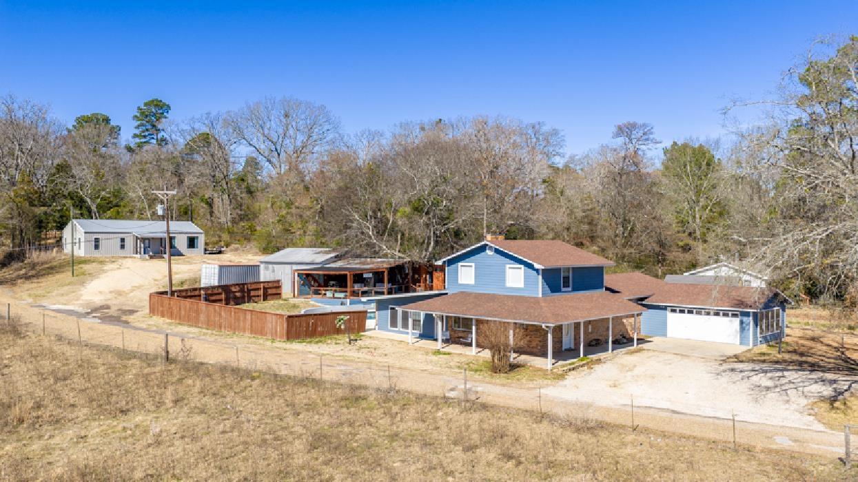 Image 2: View of front facade featuring driveway, a shingled roof, a garage, and view of wooded area, Front Of Structure