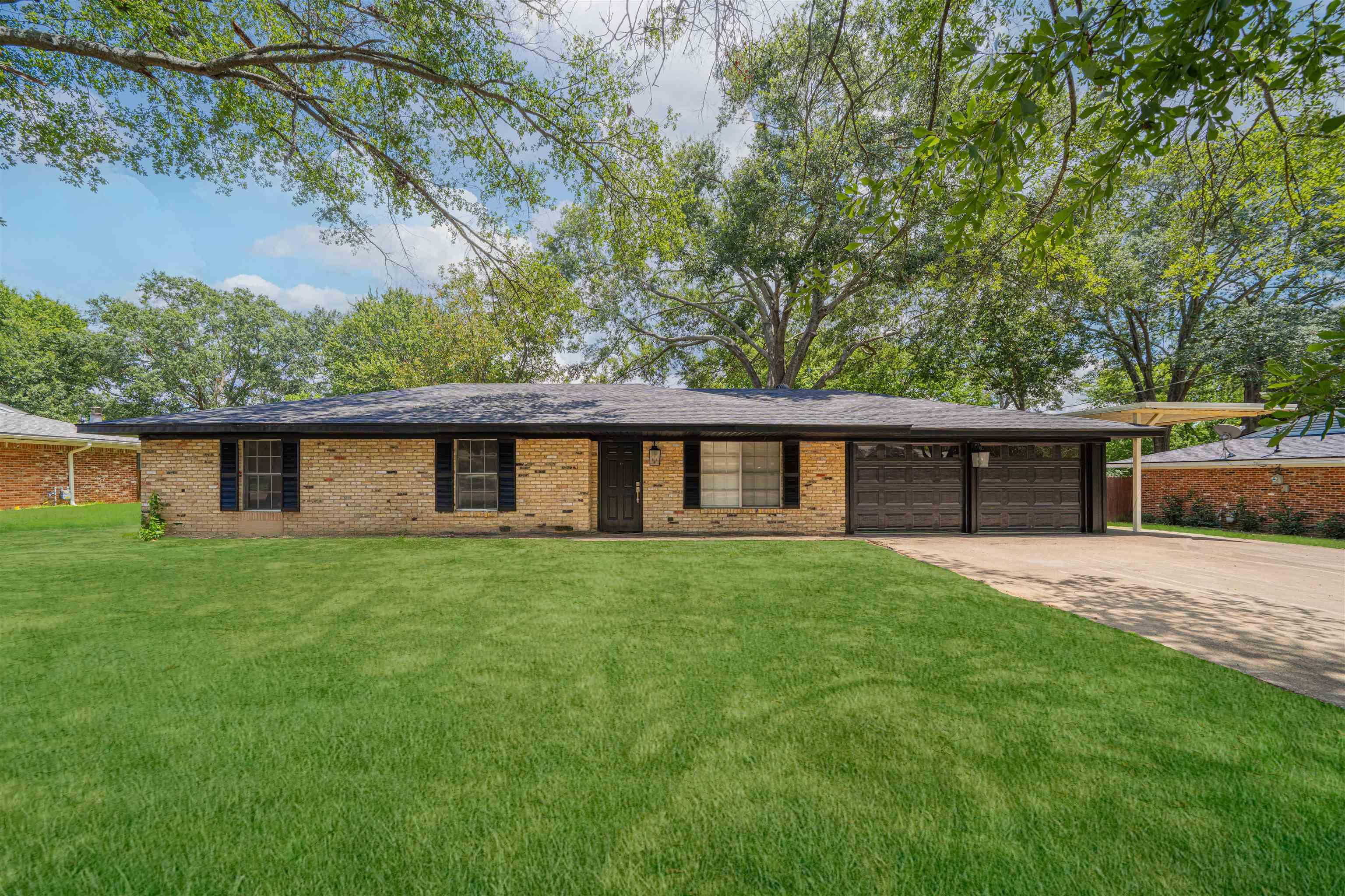 Image 0: View of front of property featuring driveway, an attached garage, a front lawn, and brick siding, Front Of Structure