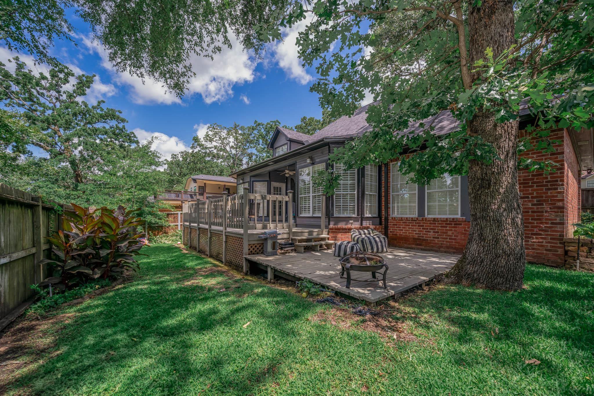 Image 3: Fenced backyard featuring a fire pit and a wooden deck, Yard
