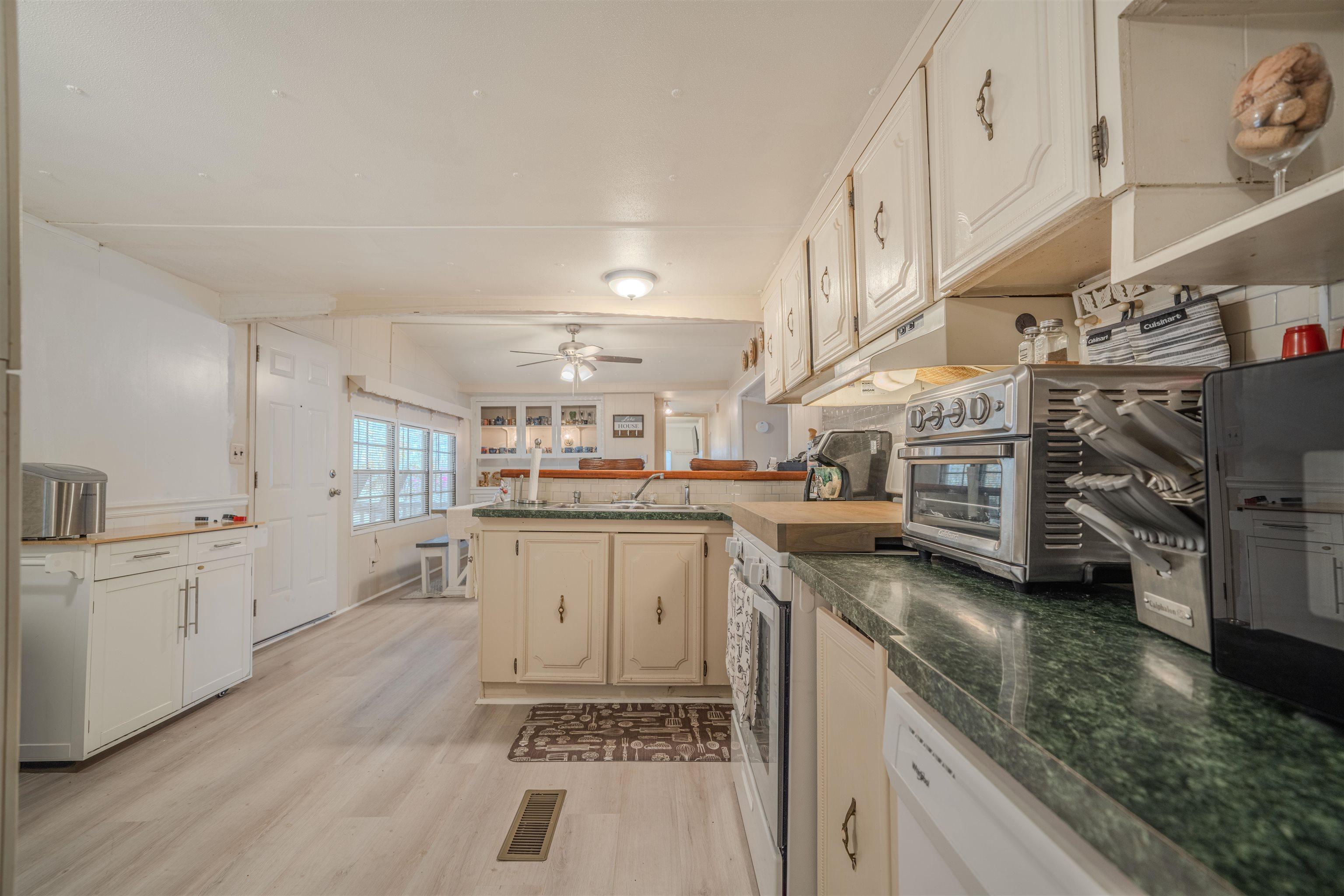 Image 2: Kitchen with light wood finished floors, a peninsula, white appliances, a ceiling fan, and white cabinets, Kitchen