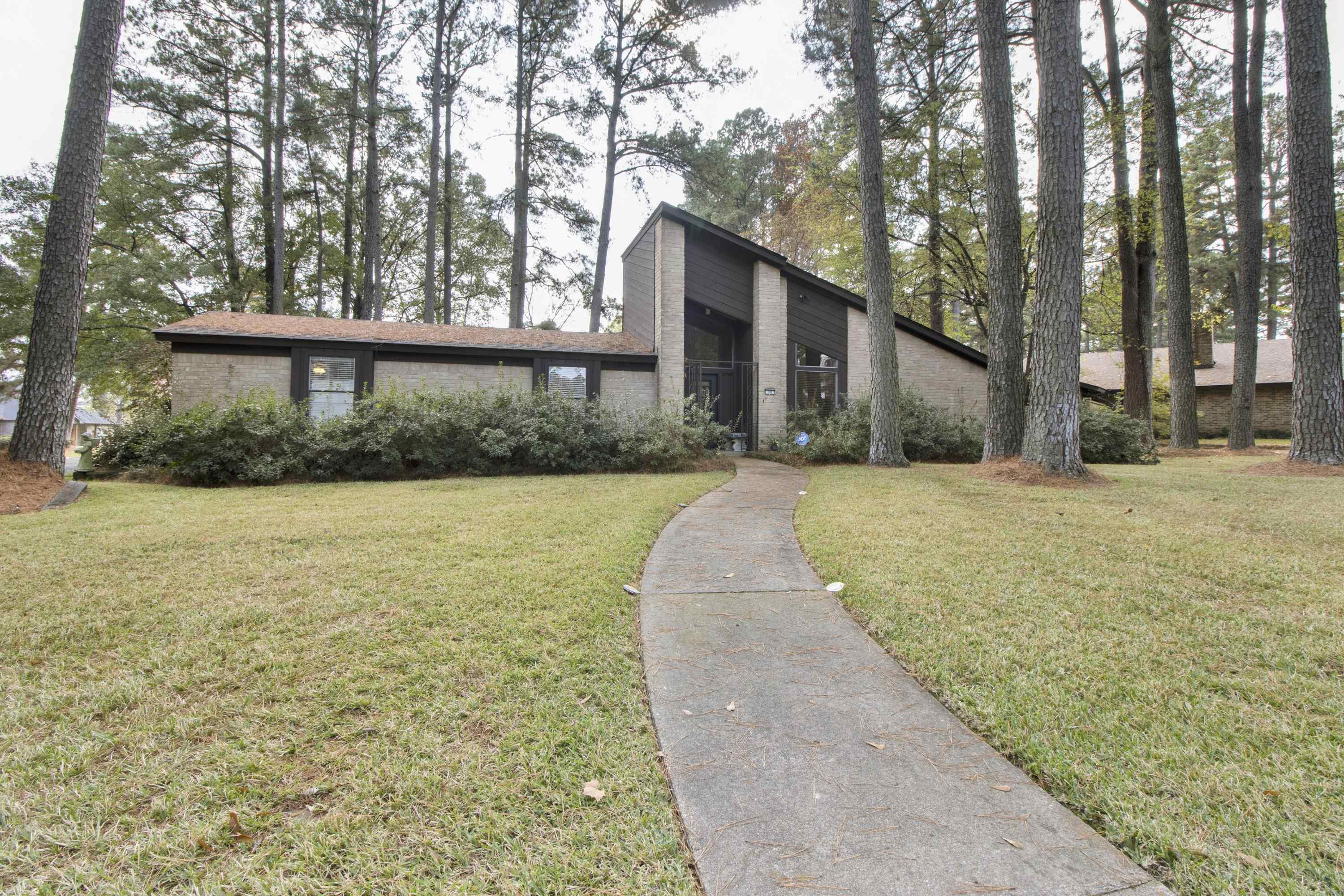 Image 0: Mid-century inspired home with a front yard, brick siding, and view of scattered trees, Front Of Structure