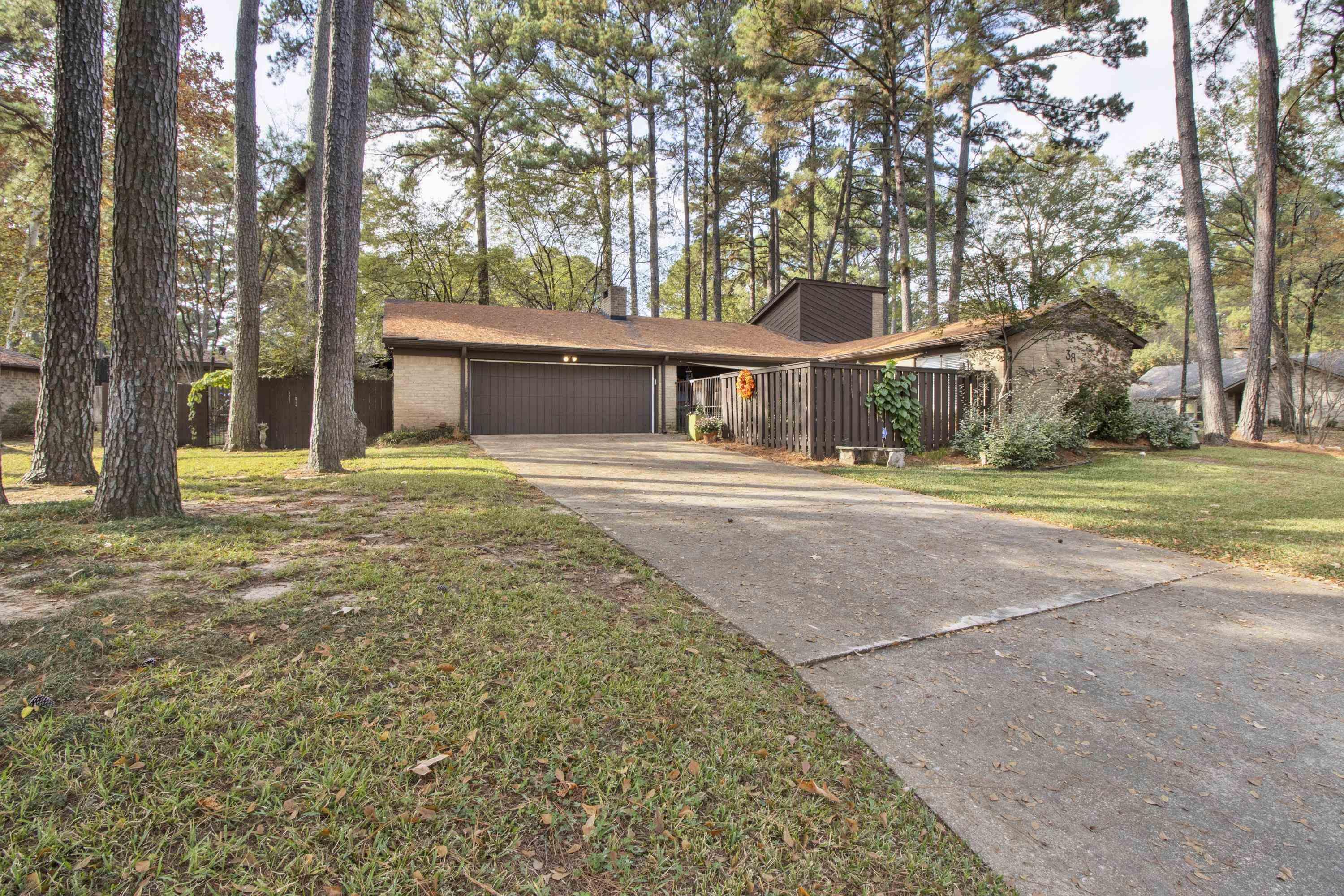 Image 3: Mid-century home with concrete driveway, a garage, a front lawn, and view of scattered trees, Front Of Structure