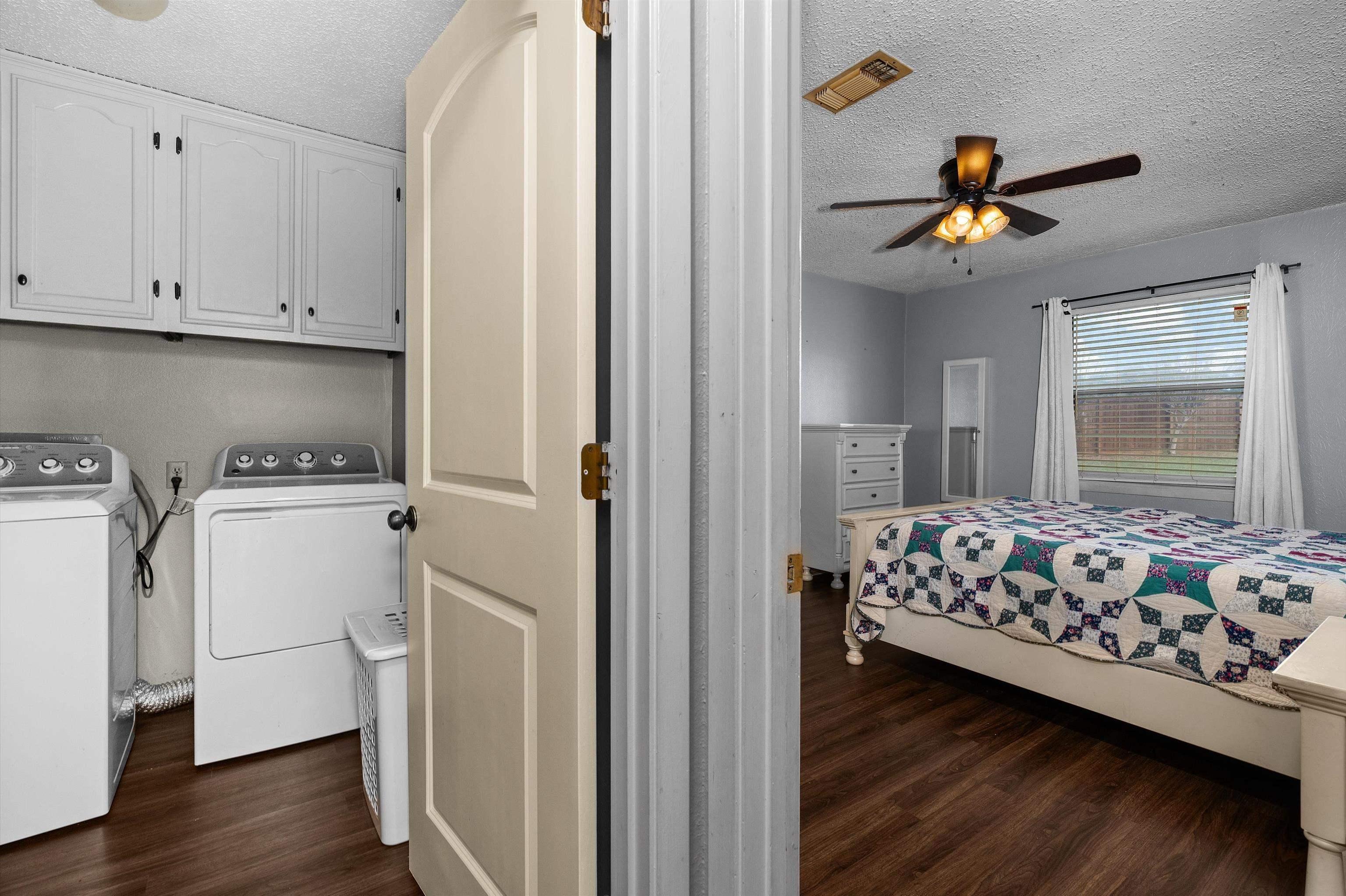 Image 2: Bedroom with dark wood-style flooring, a textured ceiling, independent washer and dryer, and ceiling fan, Bedroom