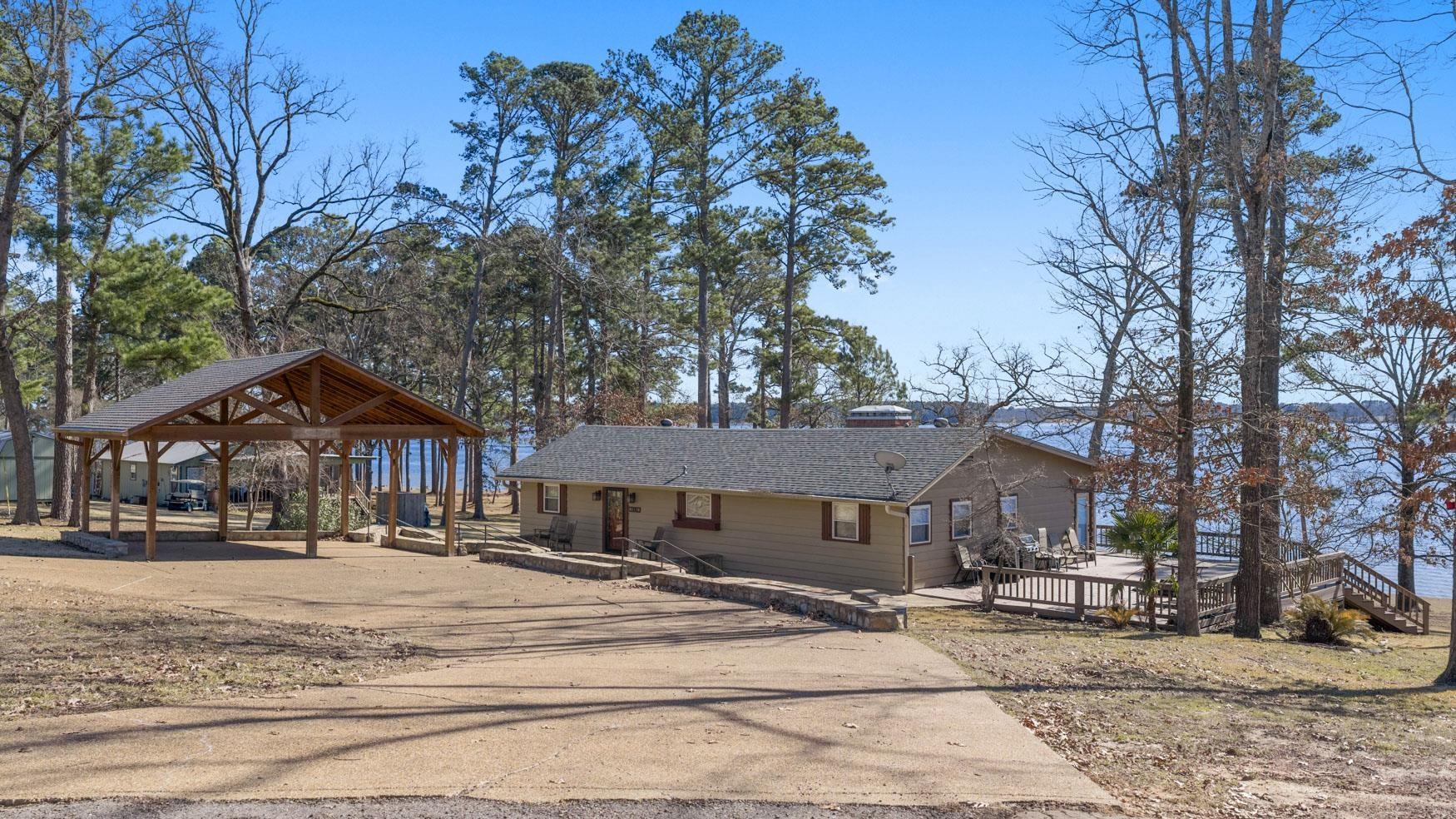 Image 0: View of front of house featuring roof with shingles, a carport, a wooden deck, and concrete driveway, Front Of Structure