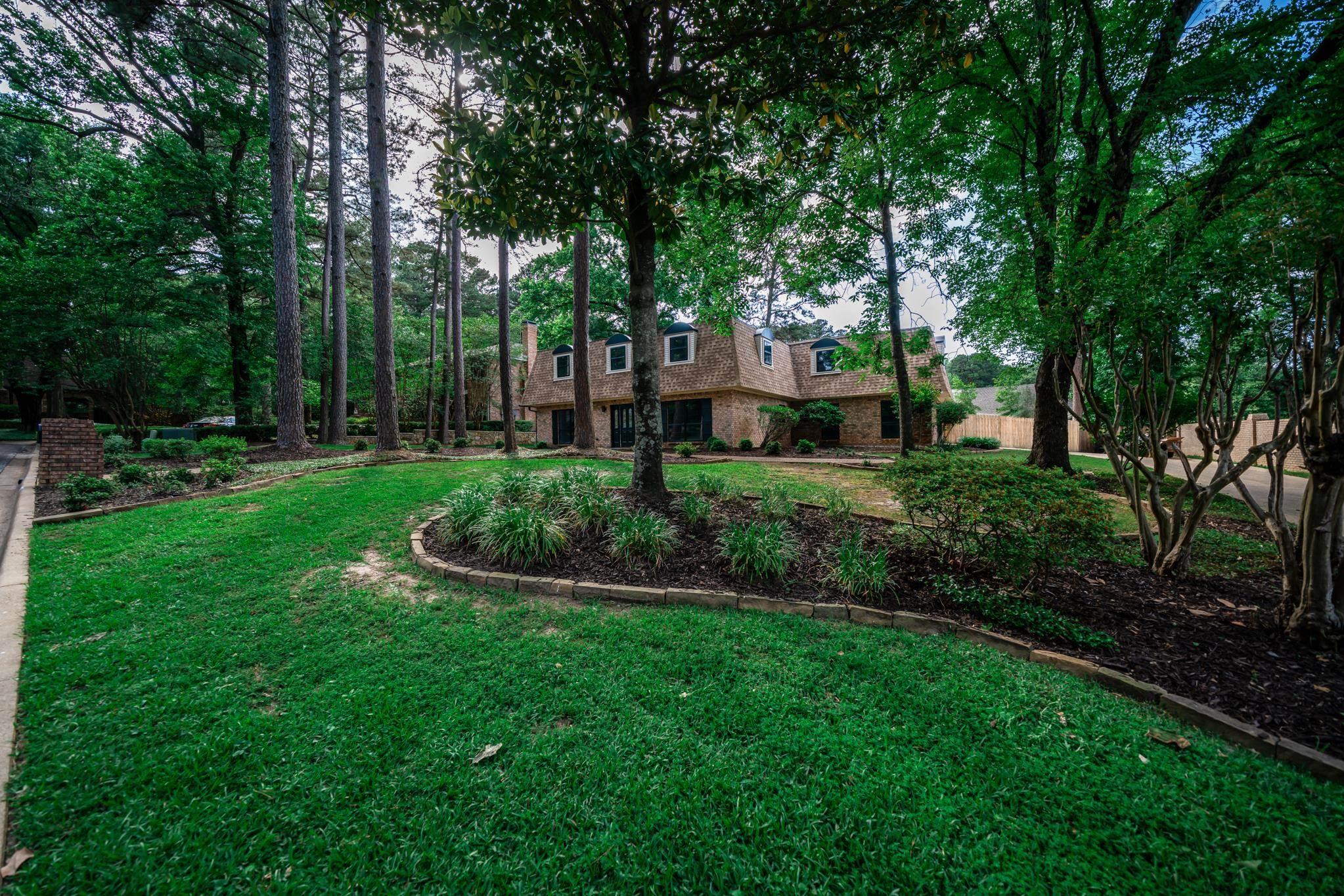 Image 1: Manicured front yard with mature trees and established landscaping beds, Yard