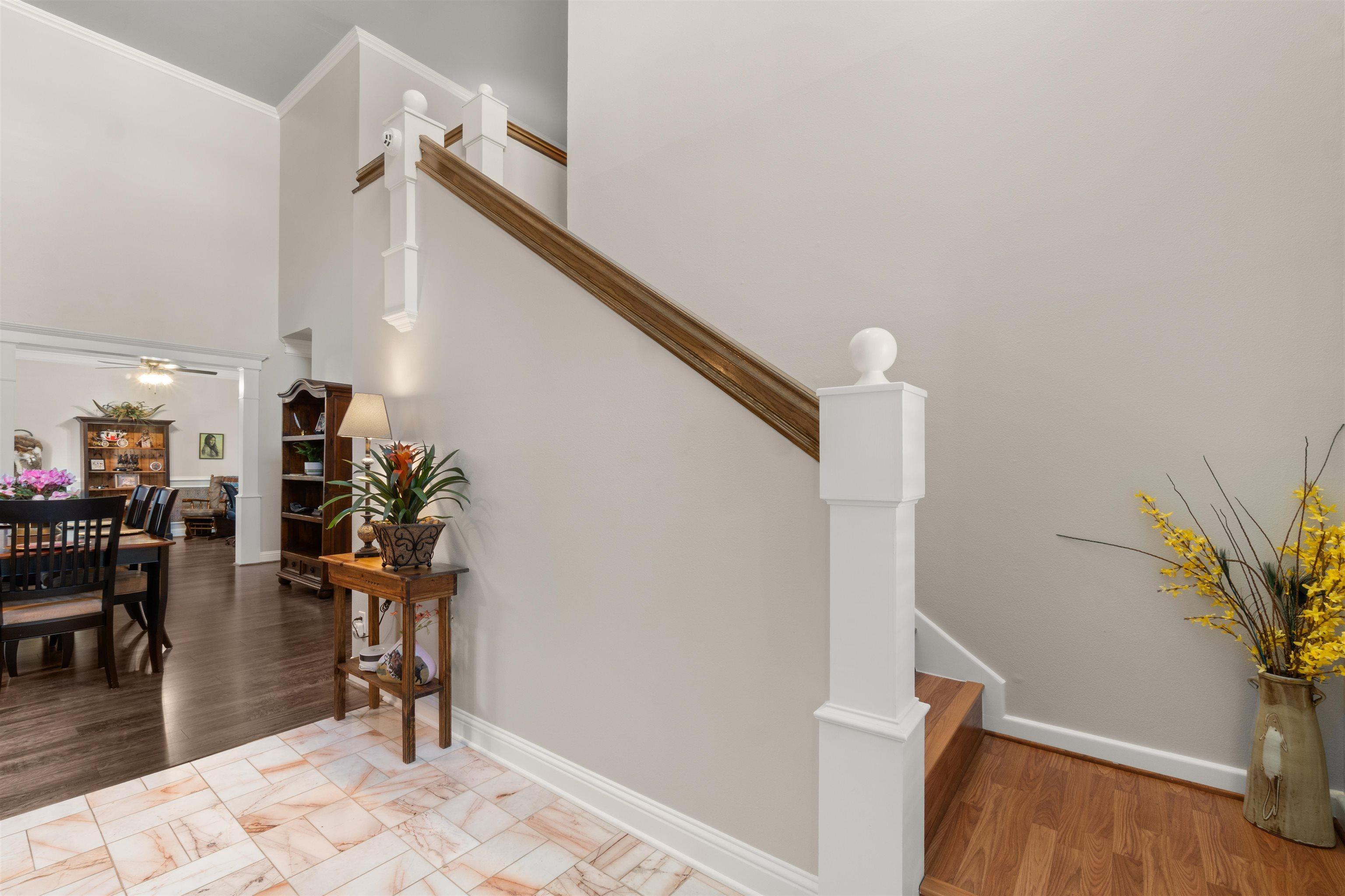 Image 2: Entryway featuring a staircase with white newel posts and wood-finish handrails, Stairs