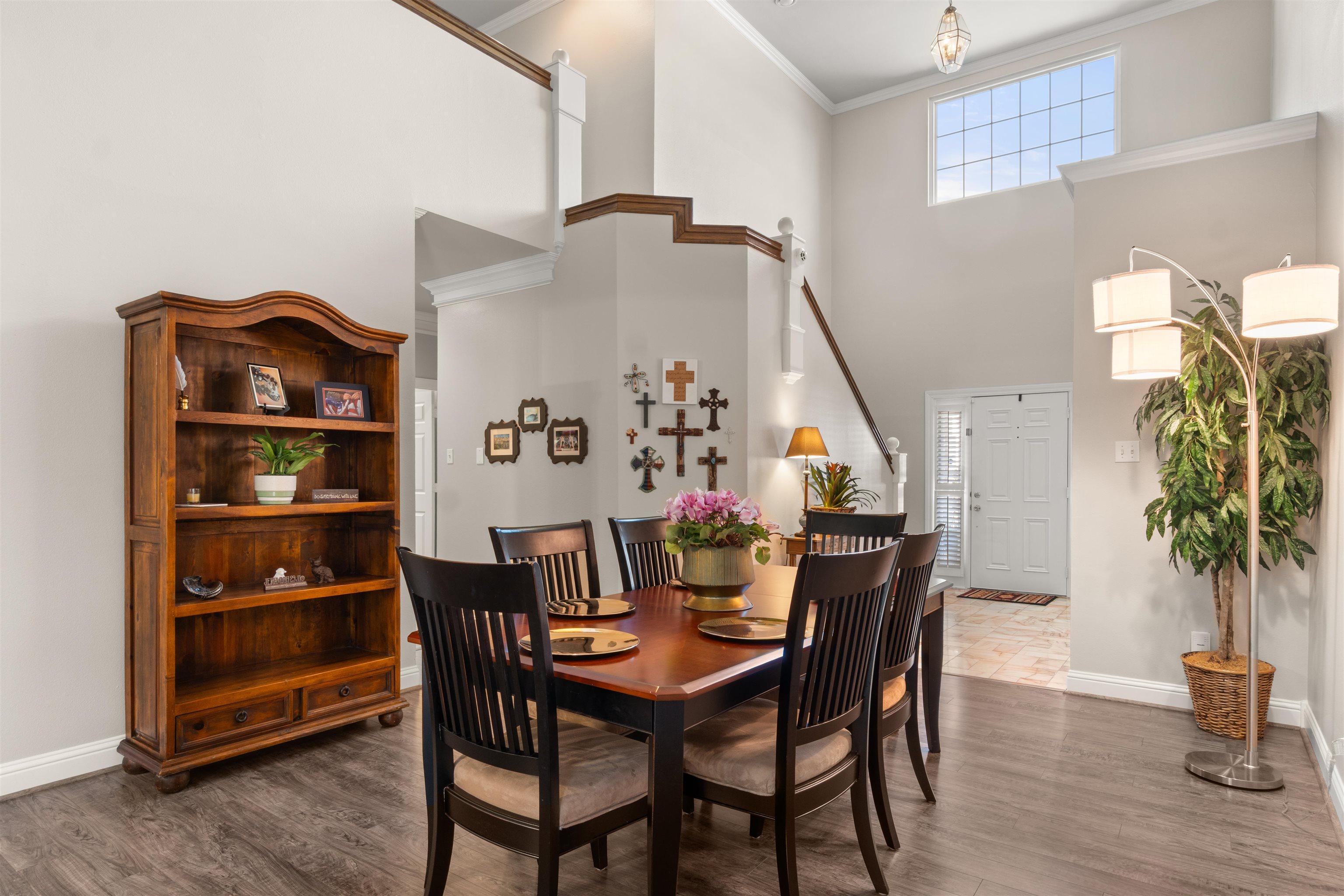 Image 3: Vaulted ceilings with a transom window create an airy dining space featuring wood-finish flooring, crown molding, and a staircase with wood railing, Dining Area