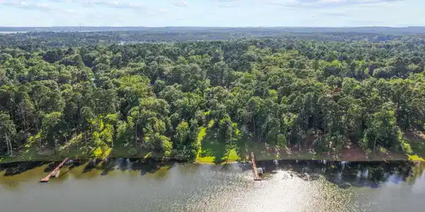 Image 1: Expansive waterfront property featuring a wooded shoreline, two private docks, and a manicured lawn, Aerial View