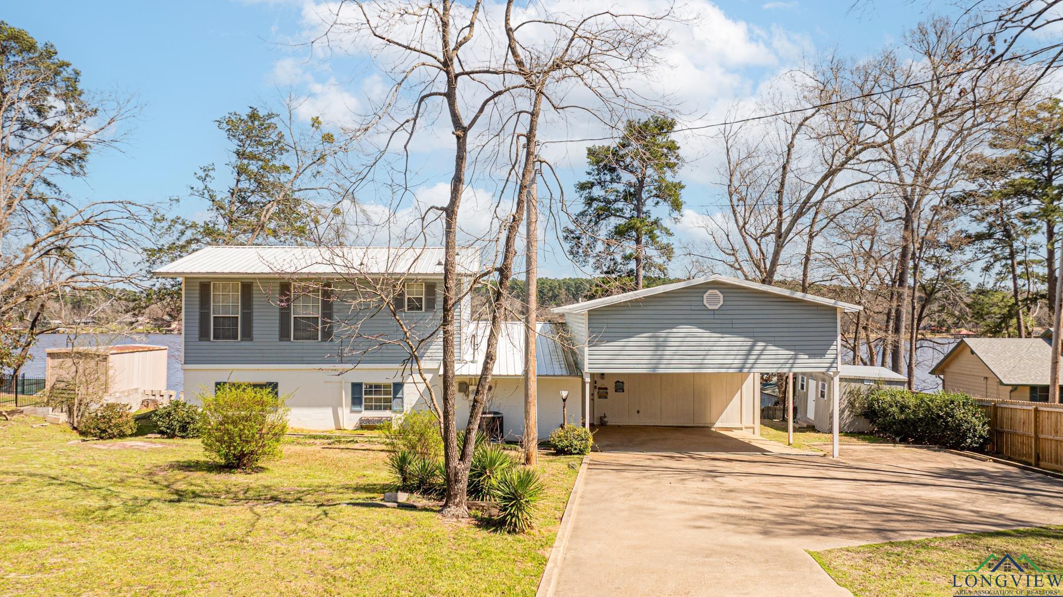 Image 0: View of front facade with a carport, driveway, a front lawn, and fence, Front Of Structure