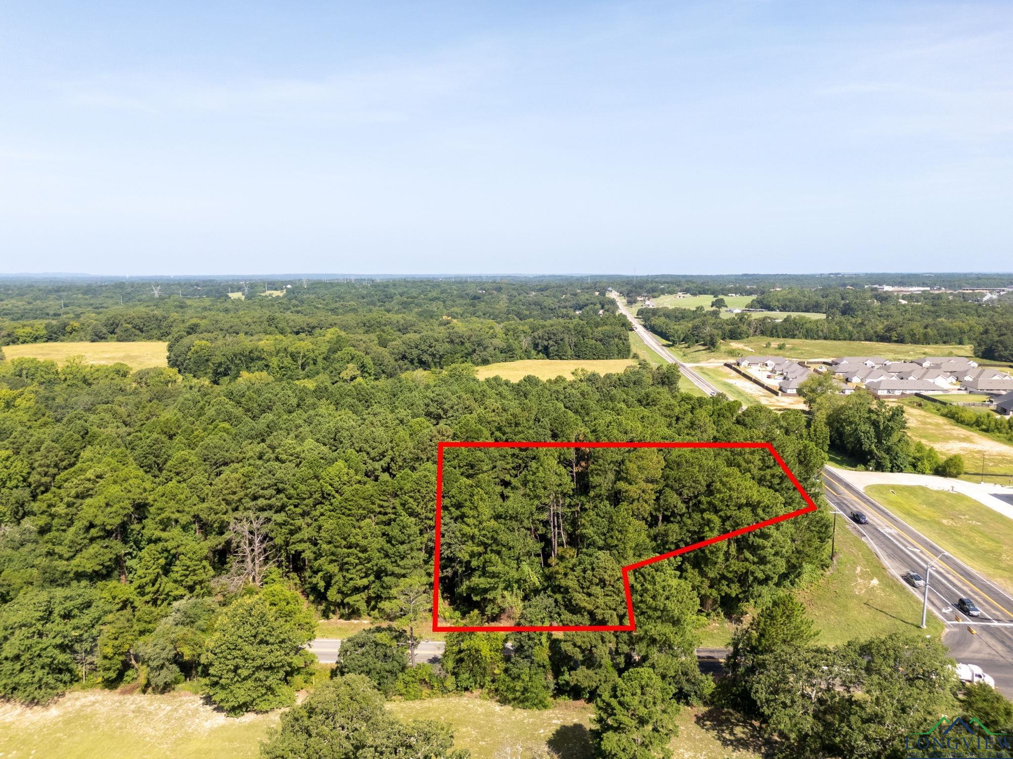 Image 1: Aerial overview of property's location with a heavily wooded area and property parcel outlined, Aerial View