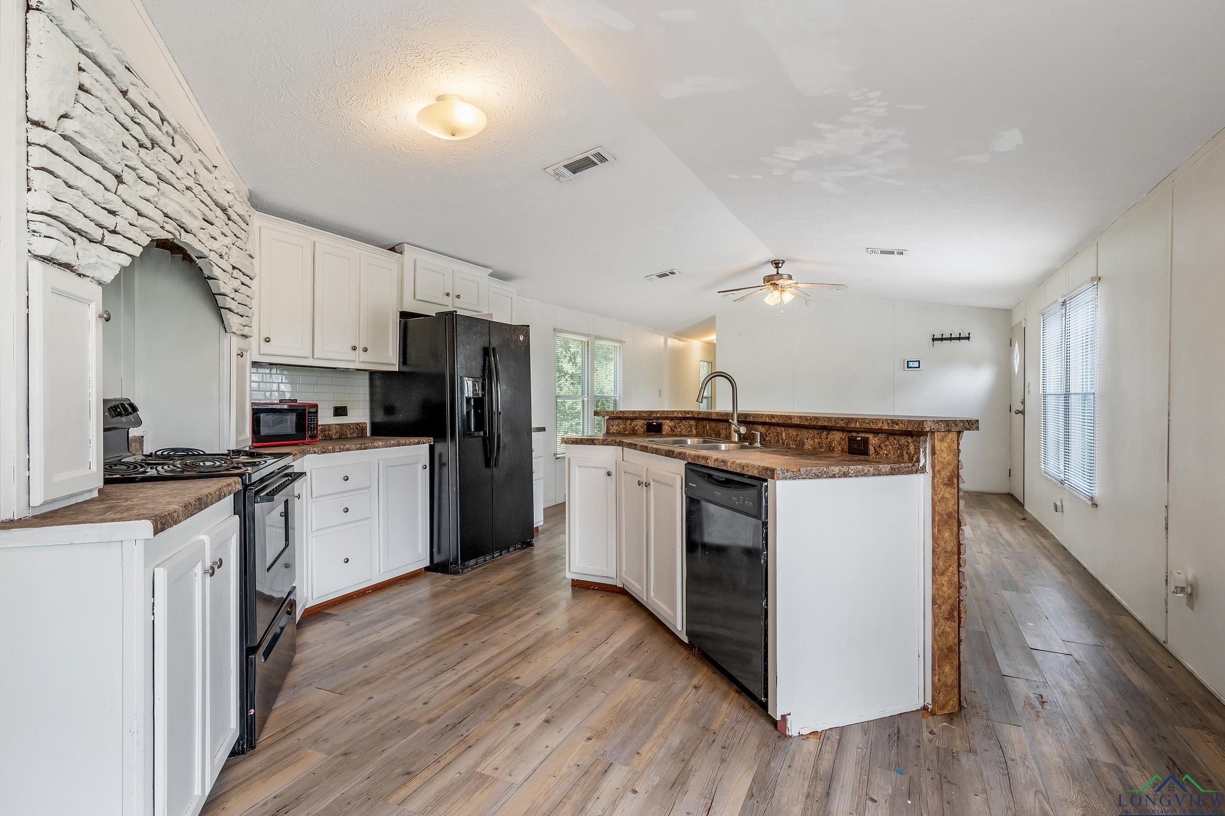 Image 3: Kitchen featuring black appliances, dark countertops, vaulted ceiling, backsplash, and light wood-type flooring, Kitchen
