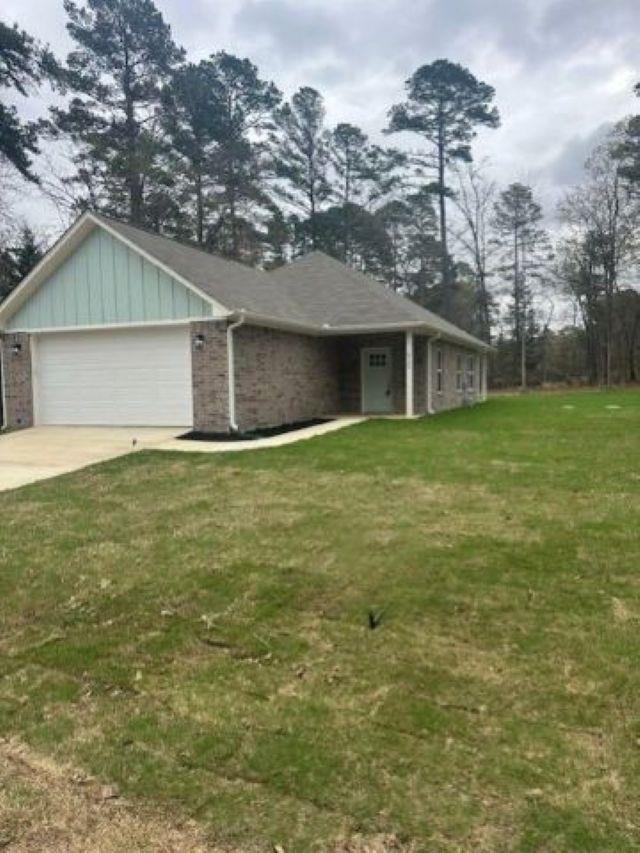 Image 2: Single story home featuring a front lawn, an attached garage, driveway, brick siding, and board and batten siding, Front Of Structure