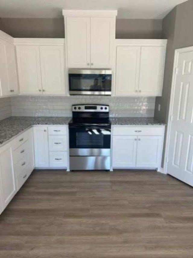 Image 3: Kitchen with stainless steel appliances, white cabinetry, dark wood-style floors, and tasteful backsplash, Kitchen