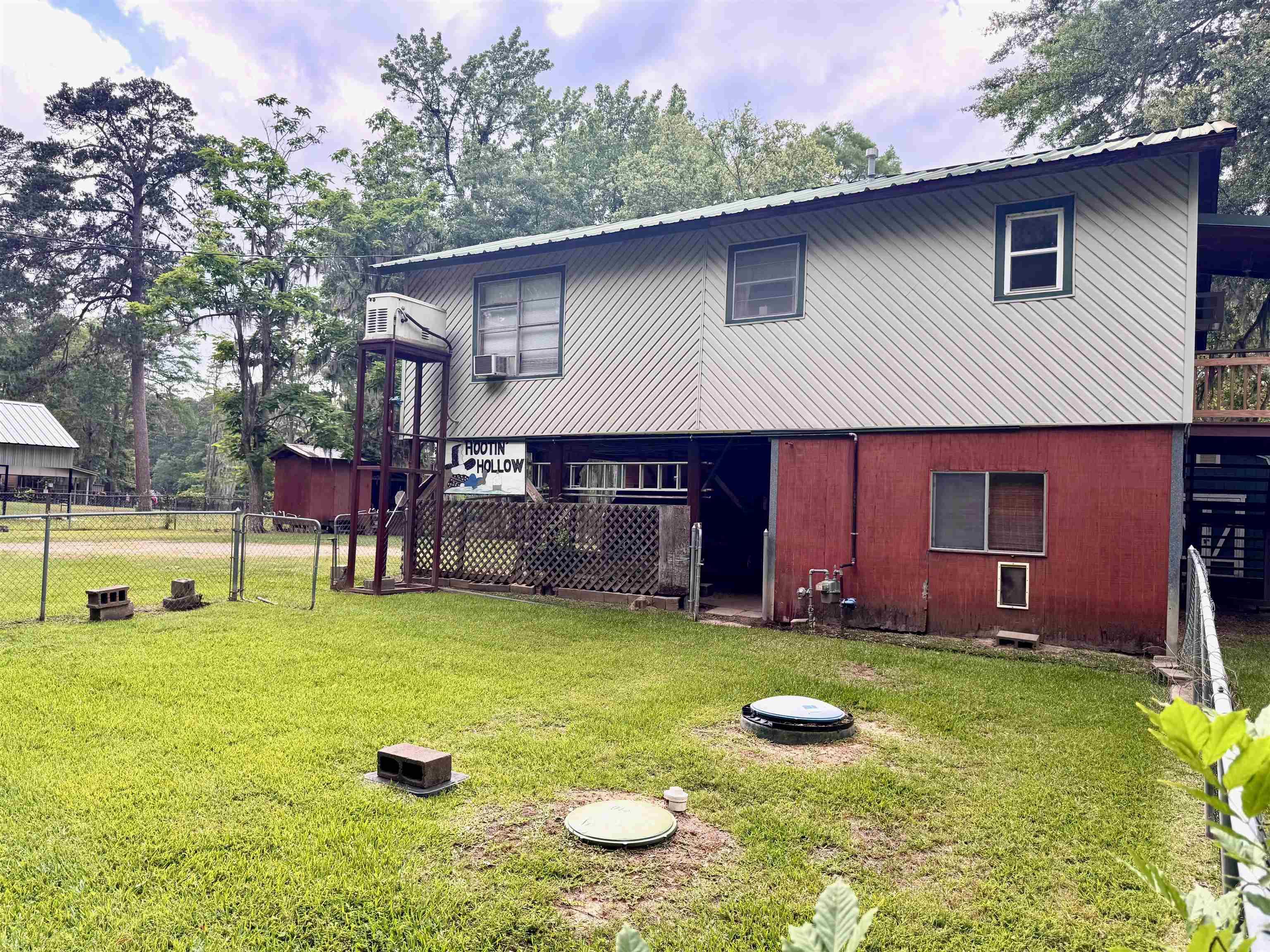 Image 1: Two-story structure with a metal roof and light-colored horizontal siding on the upper level, Back Of Structure
