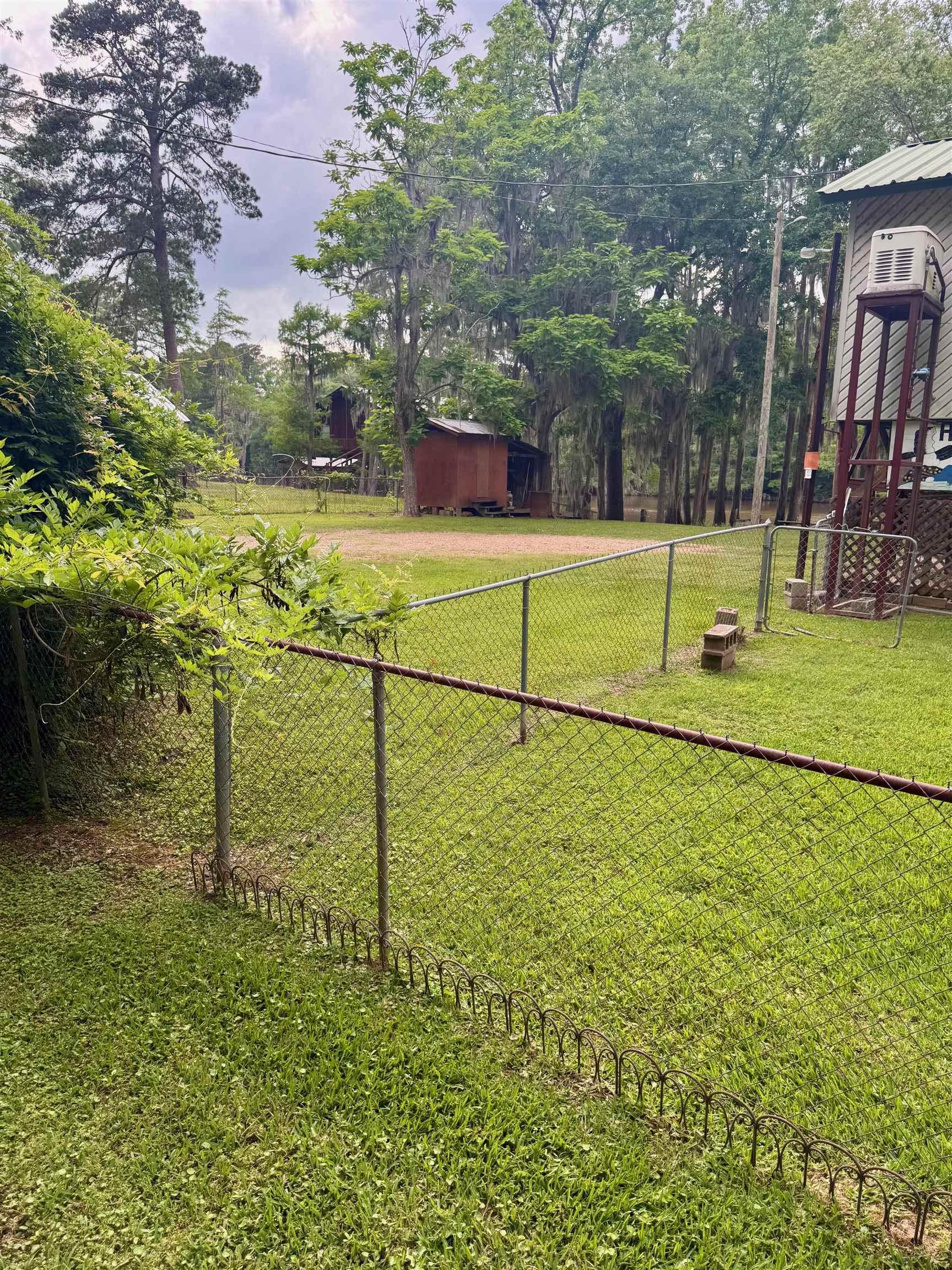 Image 3: Expansive green lawn with chain-link fencing, Yard