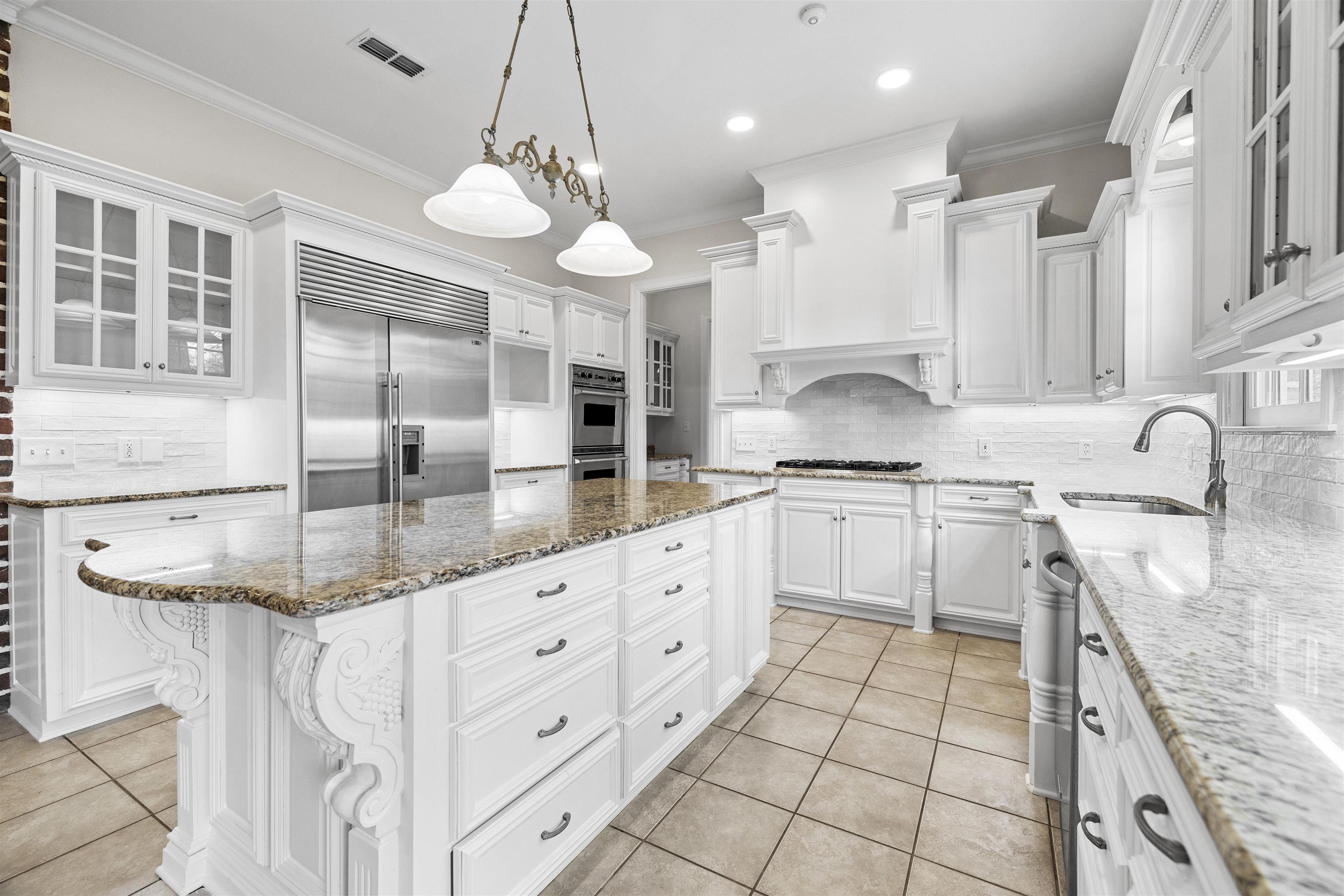 Image 1: Kitchen featuring light stone counters, white cabinets, tasteful backsplash, and crown molding, Kitchen