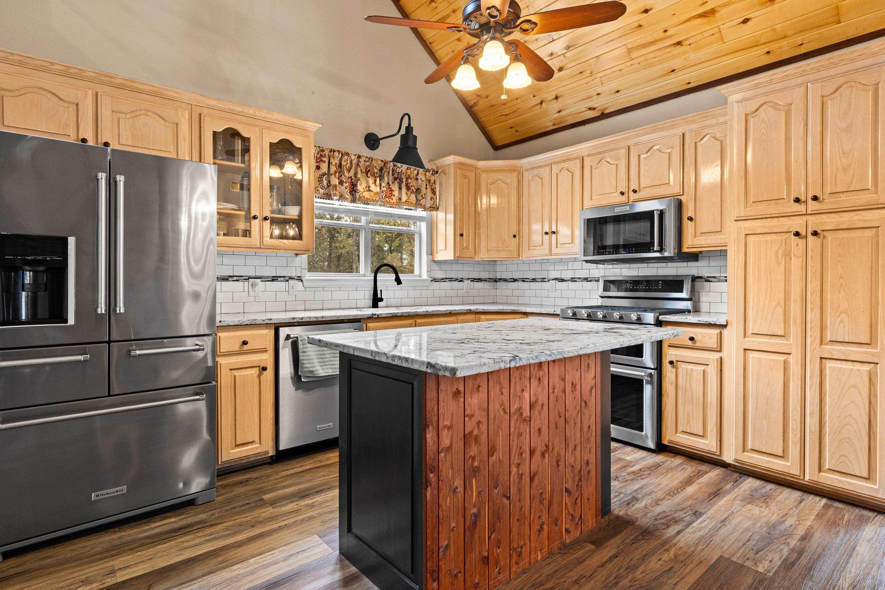 Image 1: Kitchen featuring stainless steel appliances, ceiling fan, light stone countertops, tasteful backsplash, and dark wood-style floors, Kitchen