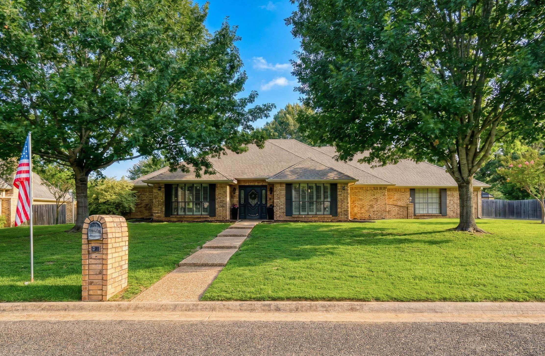 Image 0: Brick ranch-style residence featuring a paved walkway, mature trees, and a brick mailbox, Front Of Structure
