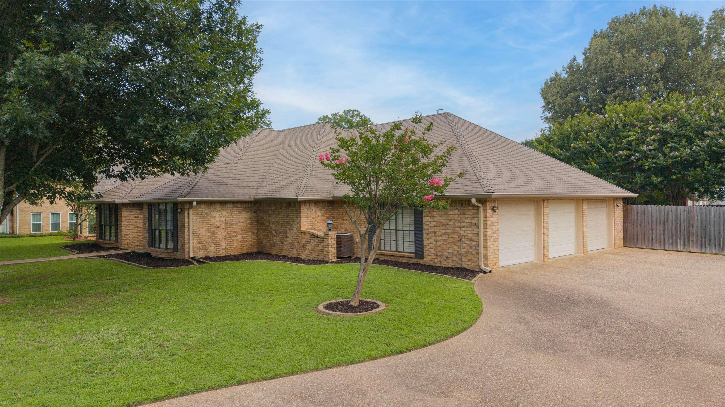 Image 2: Brick exterior with a multi-gabled roof, featuring a three-car garage, manicured front lawn, and a curved concrete driveway, Front Of Structure