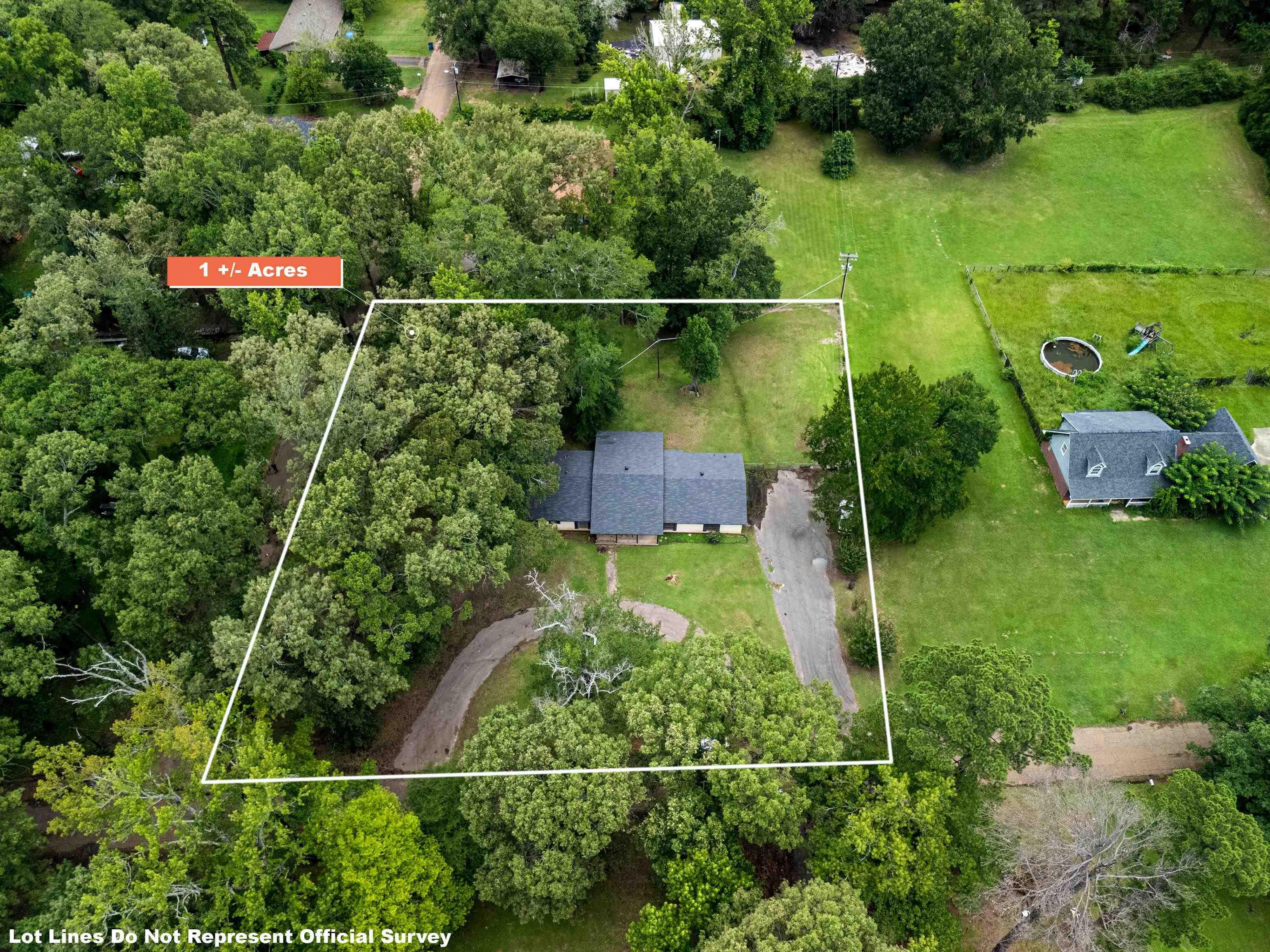 Image 2: Expansive 1+/- acre parcel featuring a single-story residence with a dark shingle roof and a curving driveway, Aerial View