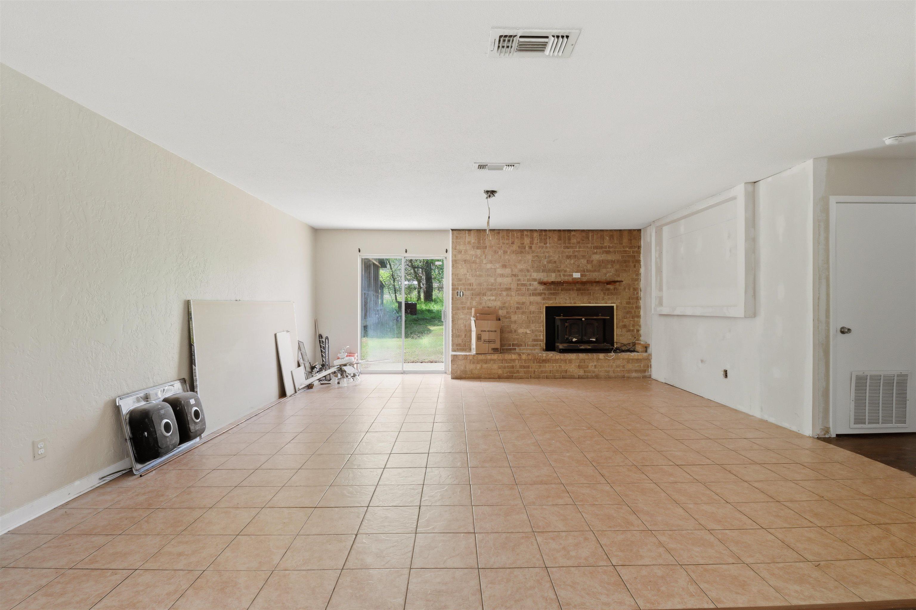 Image 1: Unfurnished living room featuring a fireplace, a textured wall, and light tile patterned floors, Living Room