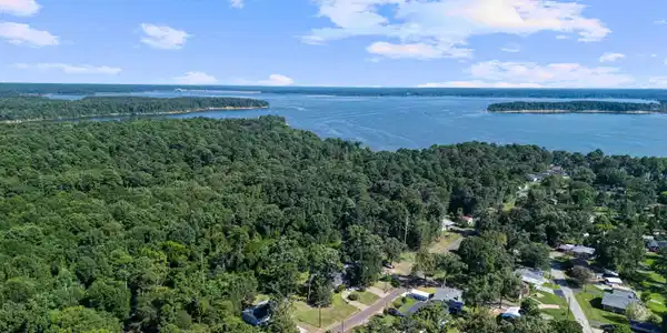 Image 2: Expansive water body bordering wooded land with residential properties, Aerial View