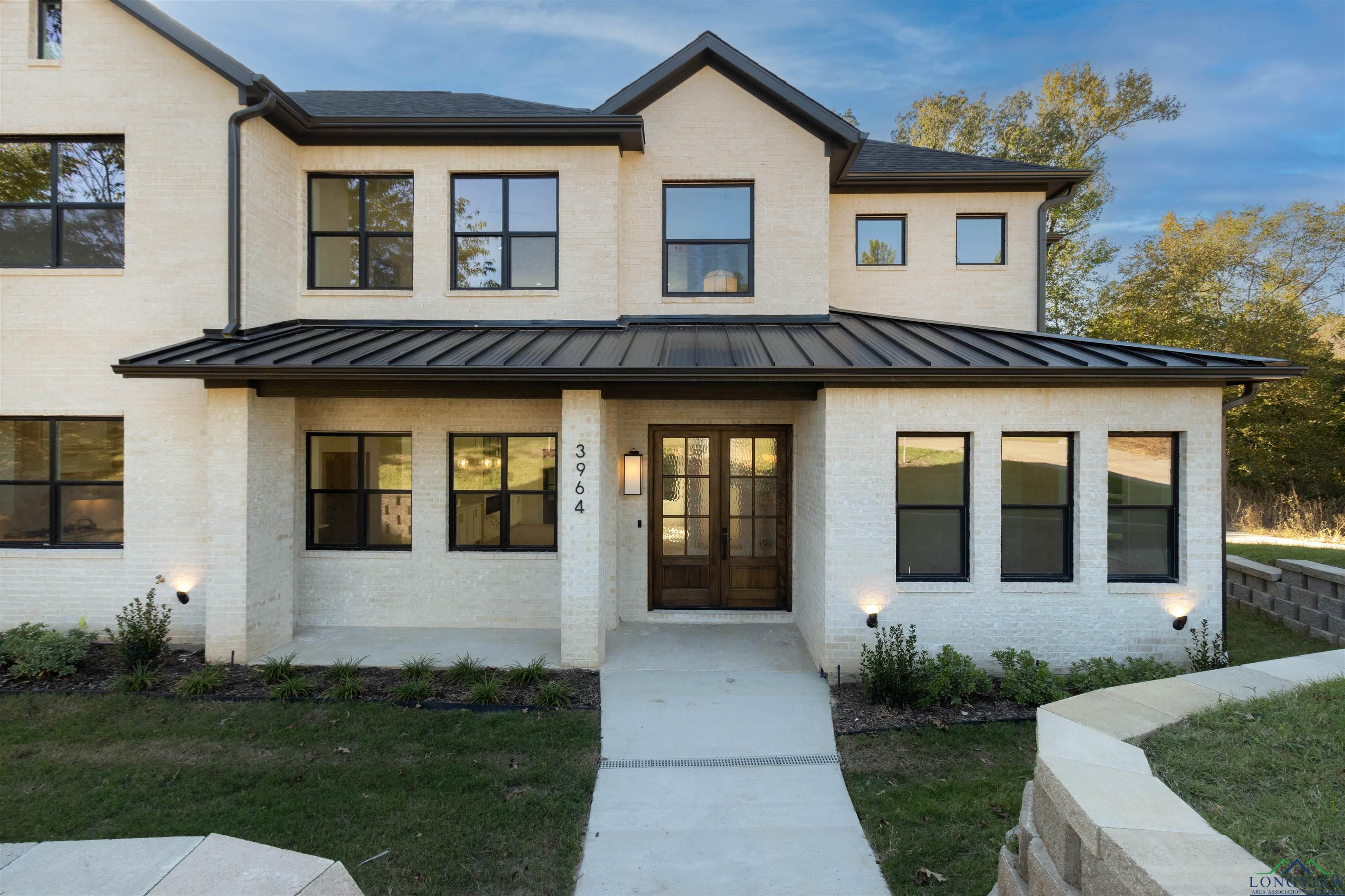 Image 1: View of front of home with brick siding, a standing seam roof, and a porch, Front Of Structure