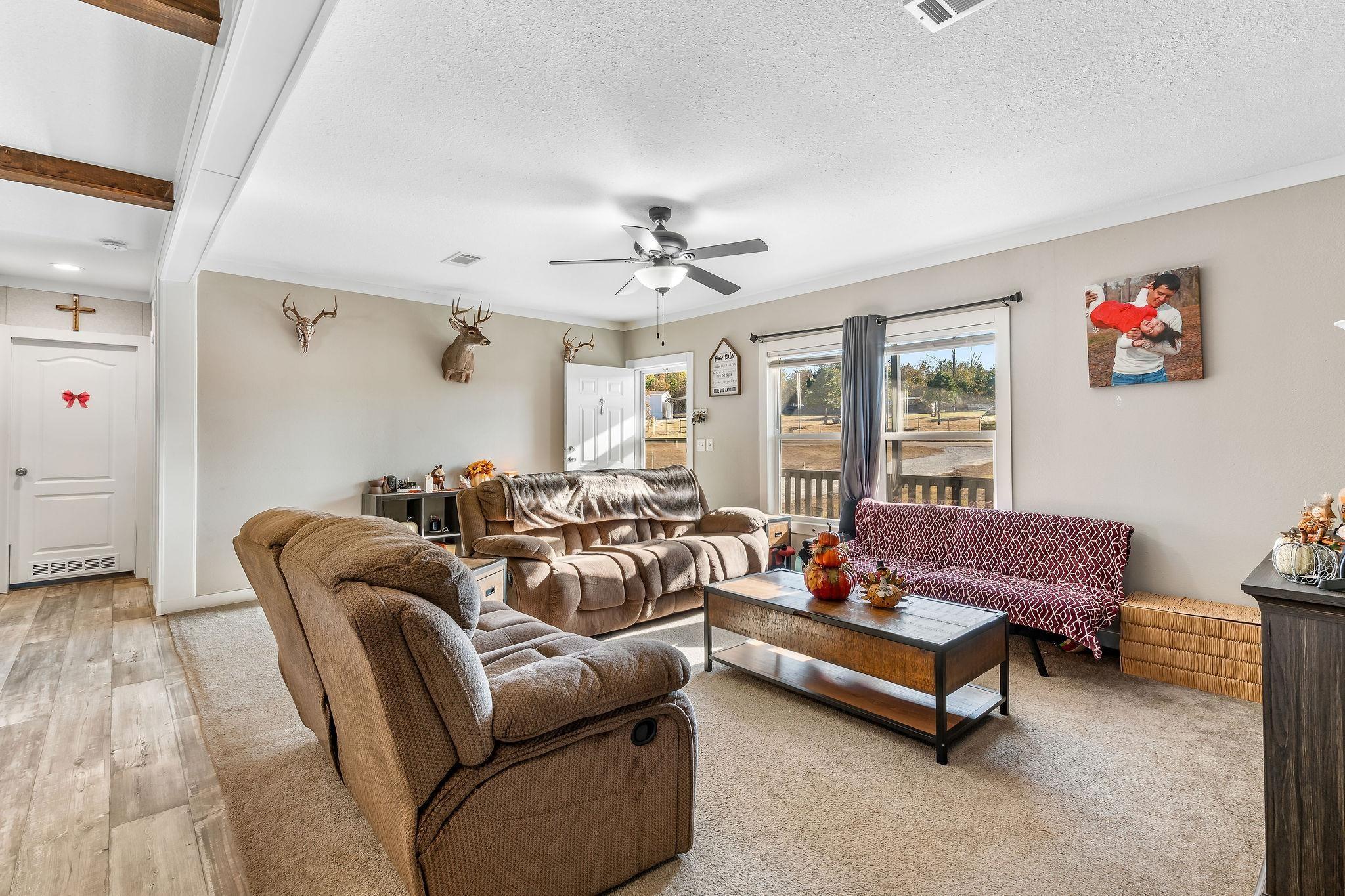 Image 3: Living area with a ceiling fan, beam ceiling, wood finished floors, and a textured ceiling, Living Room
