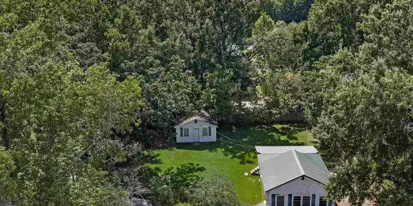 Image 1: Expansive treed lot featuring two structures and a detached shed, Aerial View