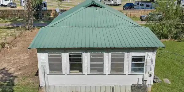 Image 3: White siding exterior with a green metal roof, Side Of Structure