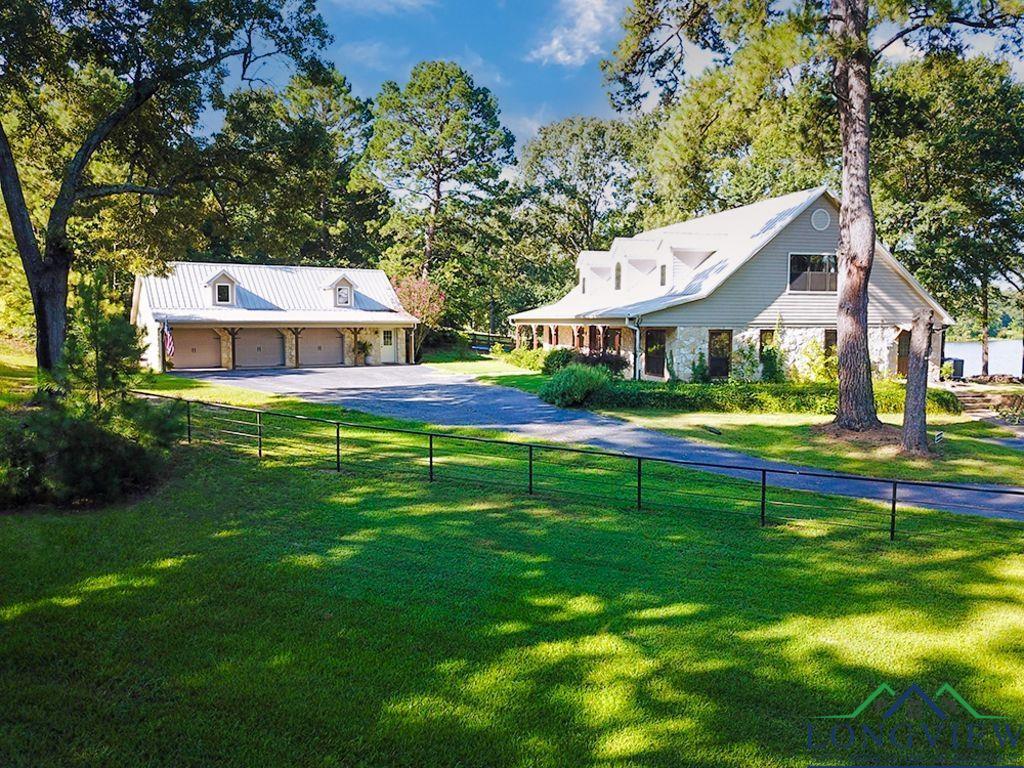 Image 3: View of yard featuring a porch, view of wooded area, driveway, and a garage, Yard