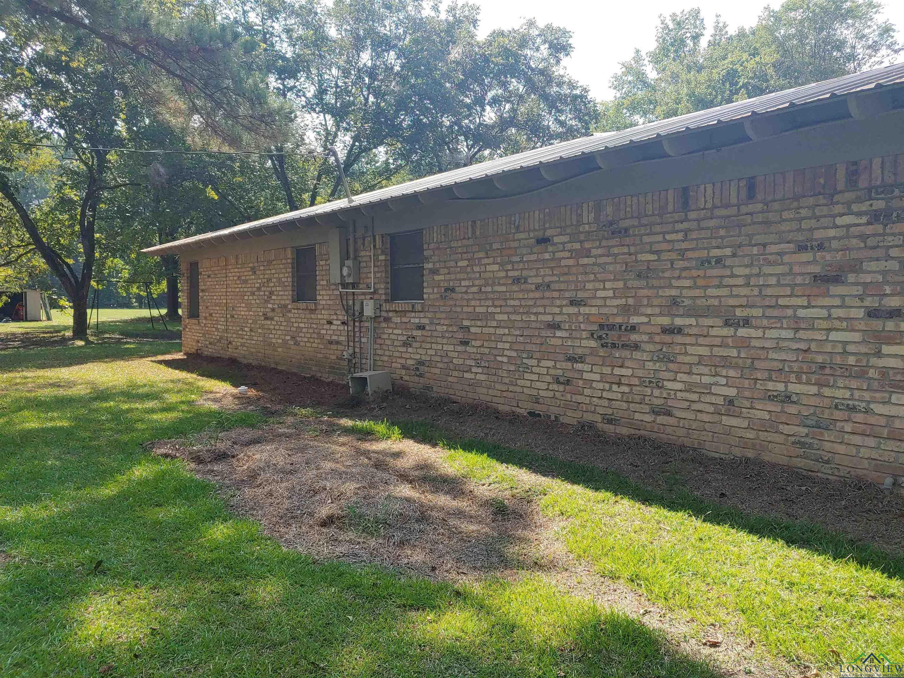 Image 3: View of side of property featuring brick exterior and lawn with aerobic., Side Of Structure